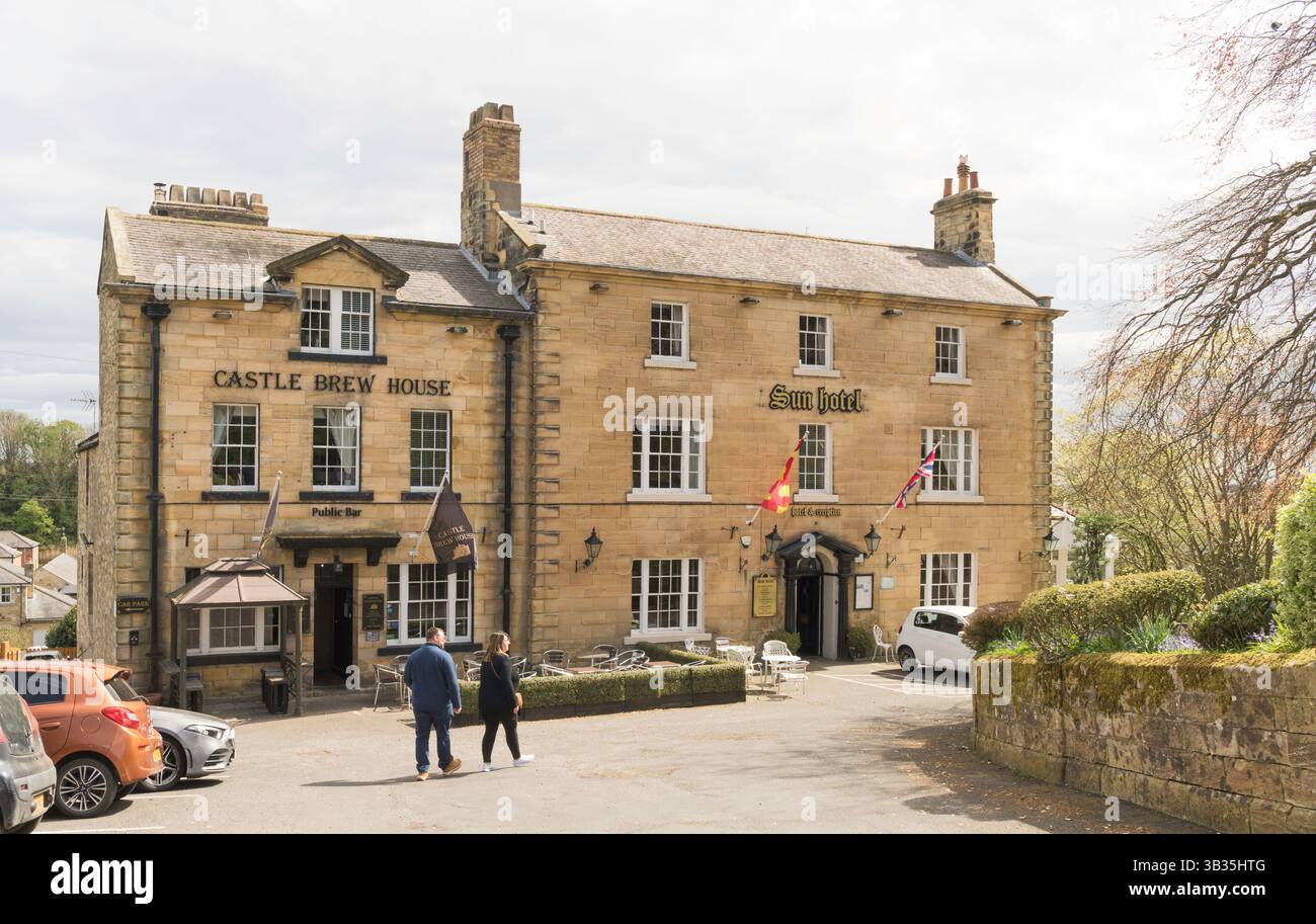 Ein Paar geht in Richtung des denkmalgeschützten Sun Hotel aus dem 18. Jahrhundert und des Castle Brew House in Warkworth, Northumberland, England, Großbritannien Stockfoto