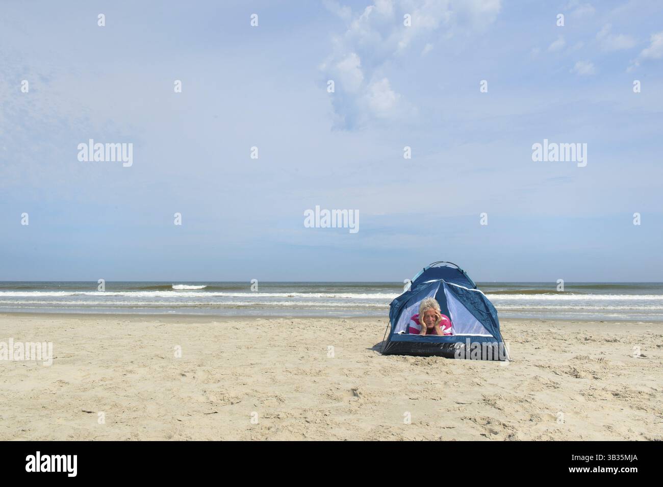 Ein älterer Mann, der im Tierheim am Strand campt Stockfoto