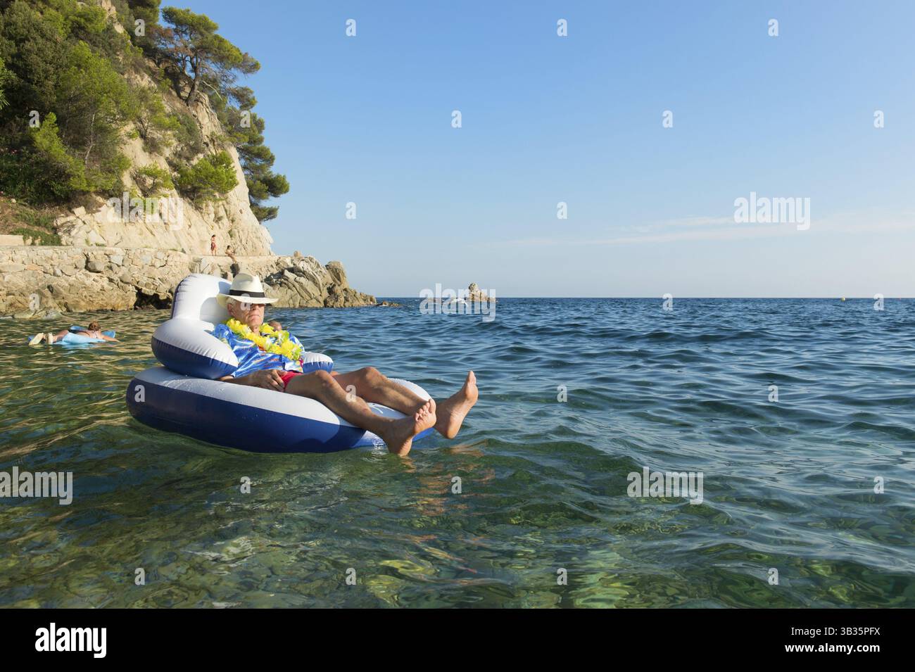 Senior woman mit Hawaii-Hemd und Blumen schweben am Meer Stockfoto