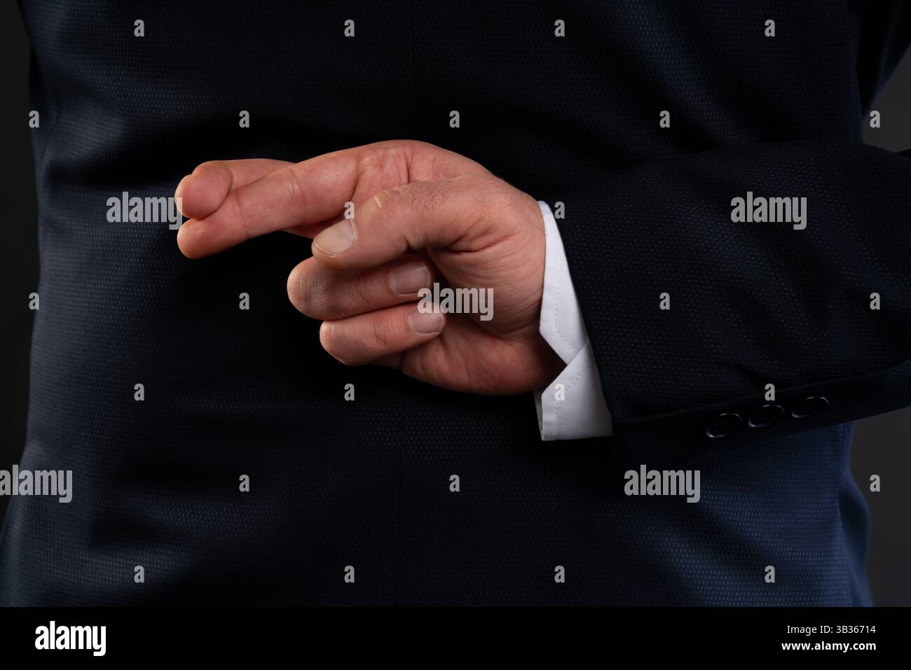 Nahaufnahme eines Mannes in einem Anzug, der die Finger hinter seinem Rücken drückt und Lügen, Unehrlichkeit oder Unaufrichtigkeit in einem geschäftlichen Kontext symbolisiert. Stockfoto