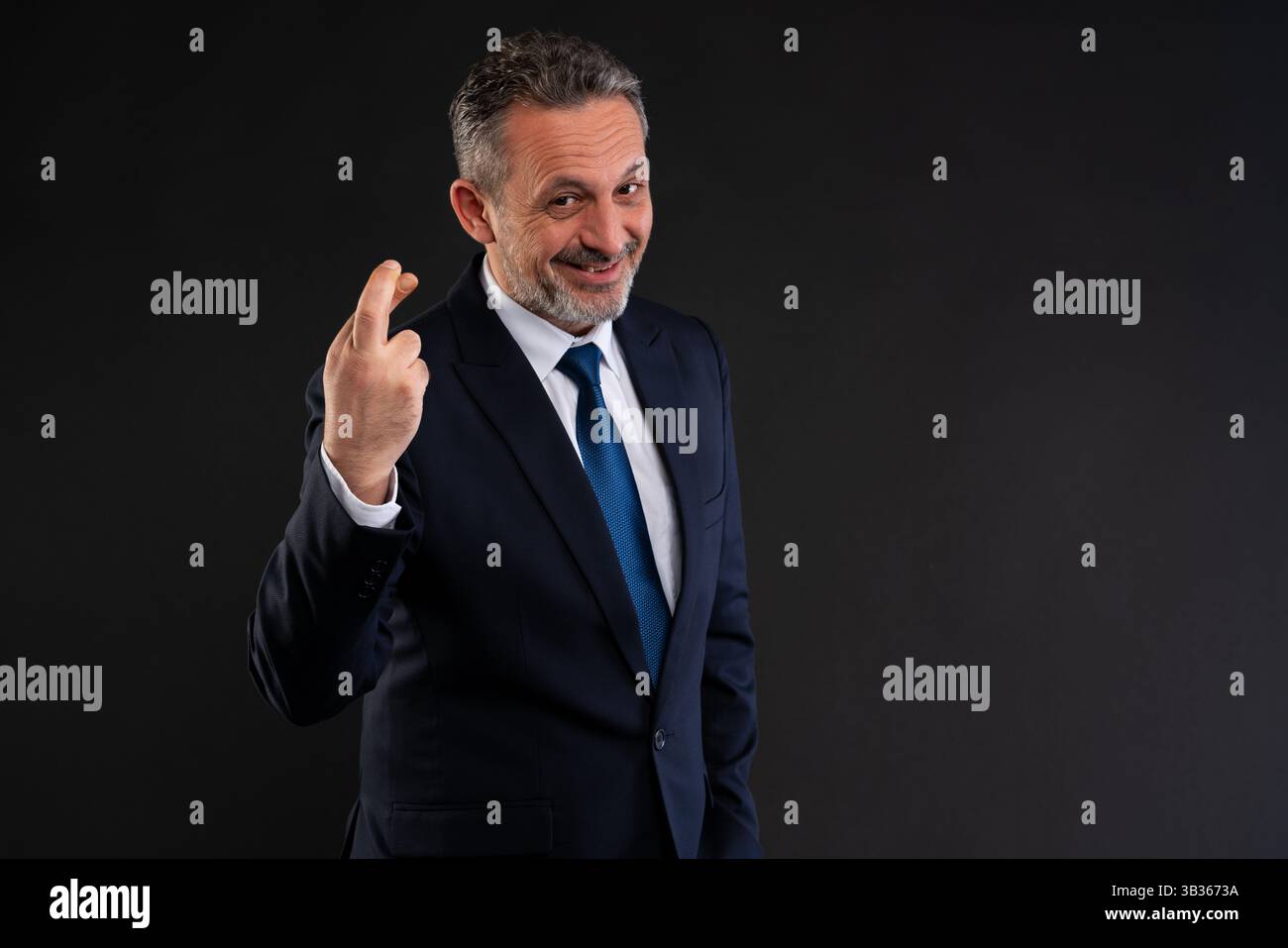 Selbstbewusster Geschäftsmann im Anzug lächelt, während er die Daumen hoch hält, und symbolisiert Glück oder Unehrlichkeit in einem geschäftlichen Kontext. Stockfoto