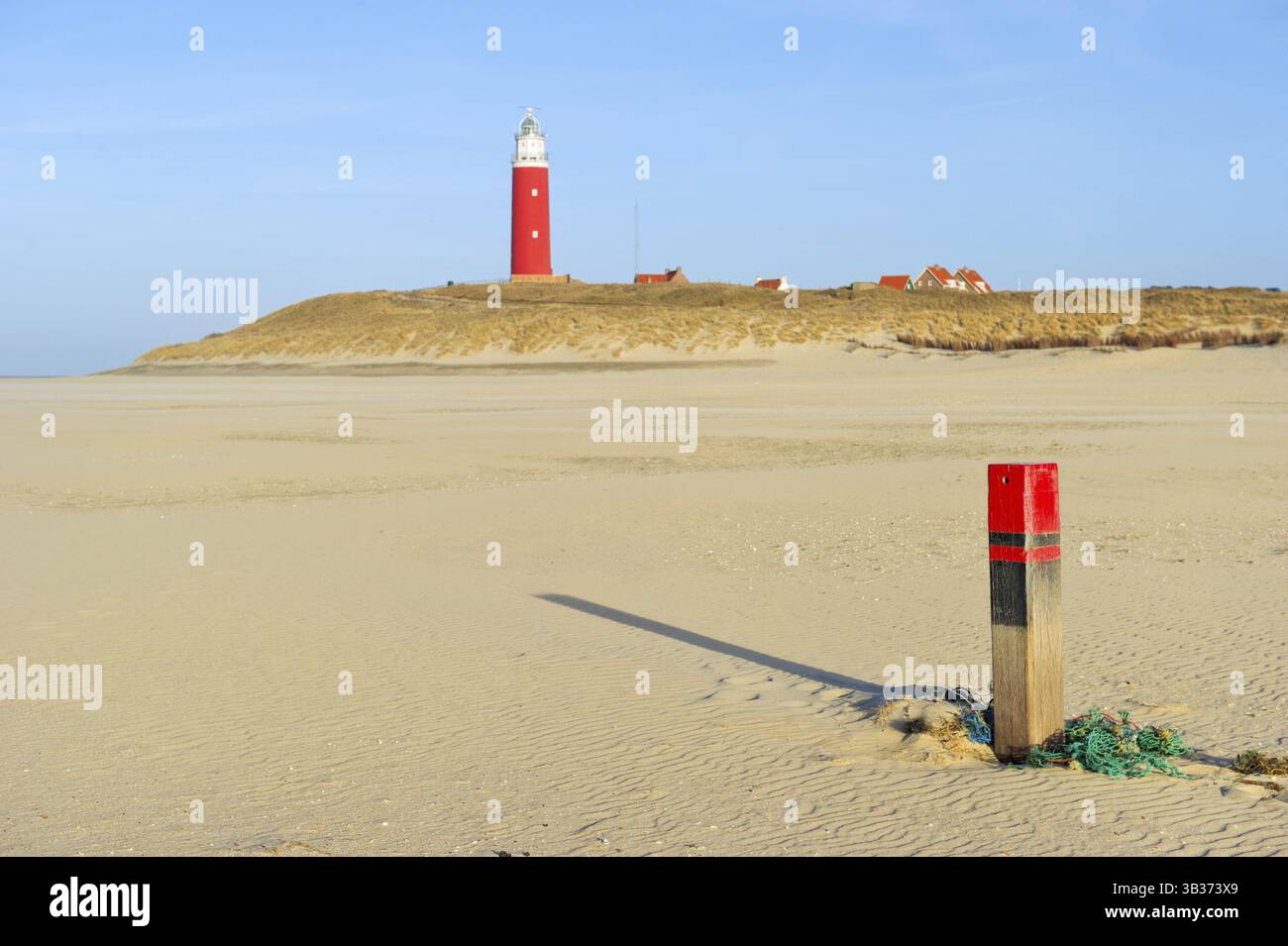 Grünes altes Fischernetz und Stange am Strand mit Leuchtturm Stockfoto