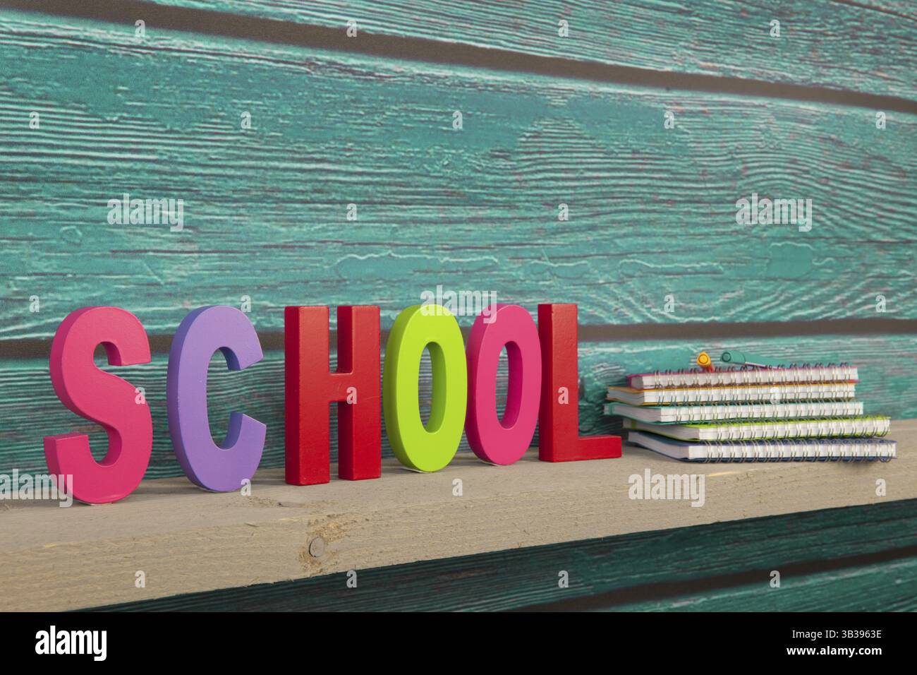 Schule in bunten Buchstaben und Notizbüchern mit Vintage blau Holz Wand Stockfoto