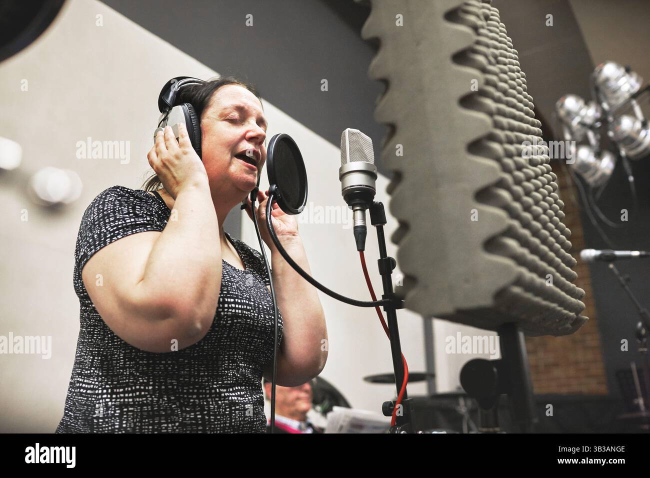 Frau, singend und Mikrofon bei der Aufnahme von Studiomusik im Rundfunk, Künstler für Albumaufführung. Weibliche Person, Kopfhörer und Audio Passion Job in Stockfoto