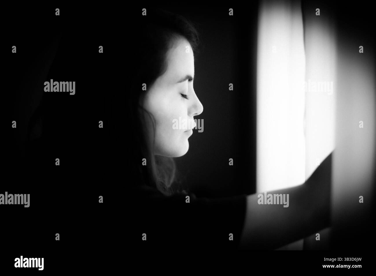 Schwarz-weiß-Porträt einer Frau mit geschlossenen Augen in weichem Licht Stockfoto