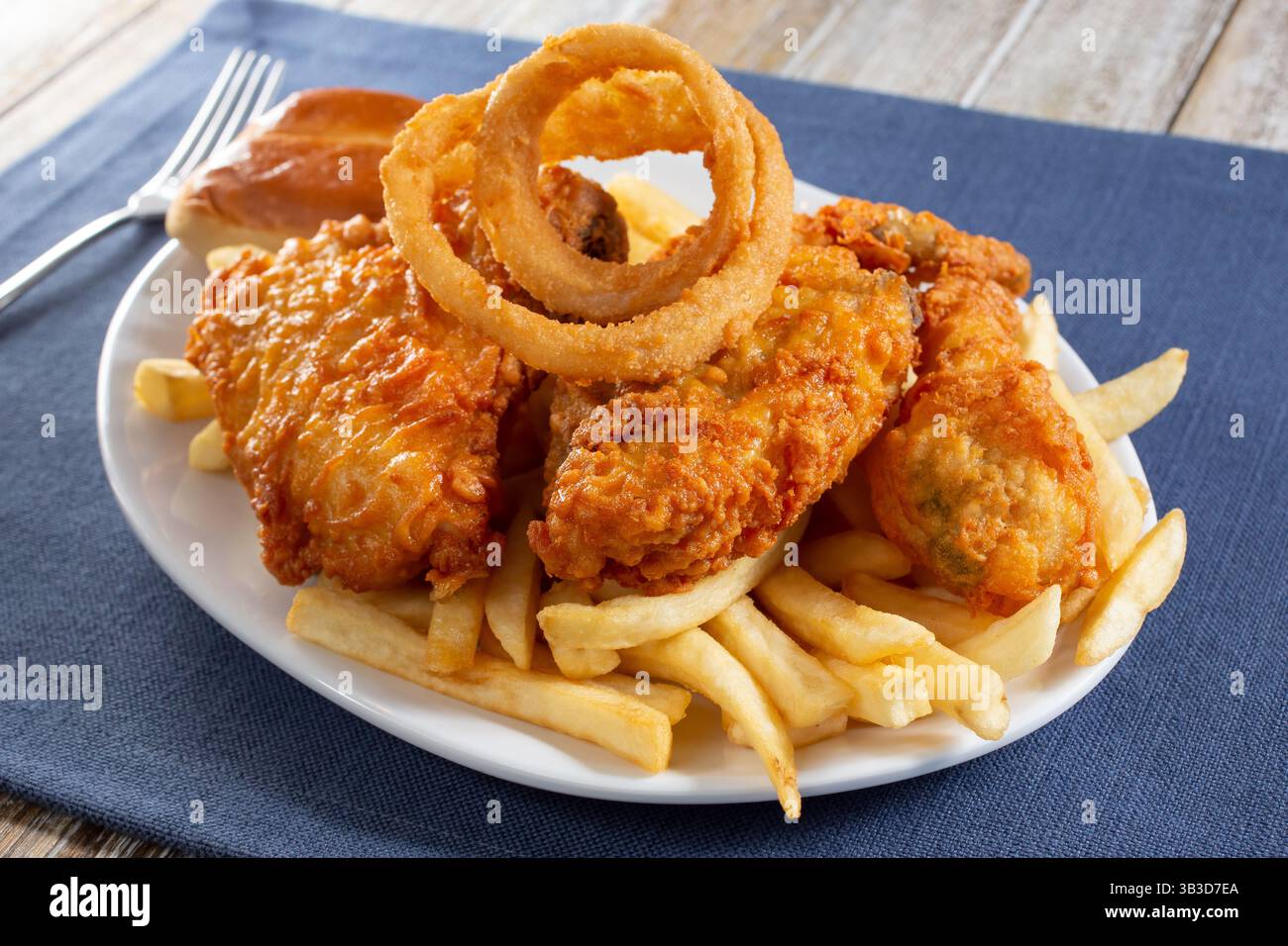 Blick auf einen Teller mit frittiertem Hühnchen, Zwiebelringen und Pommes frites. Stockfoto
