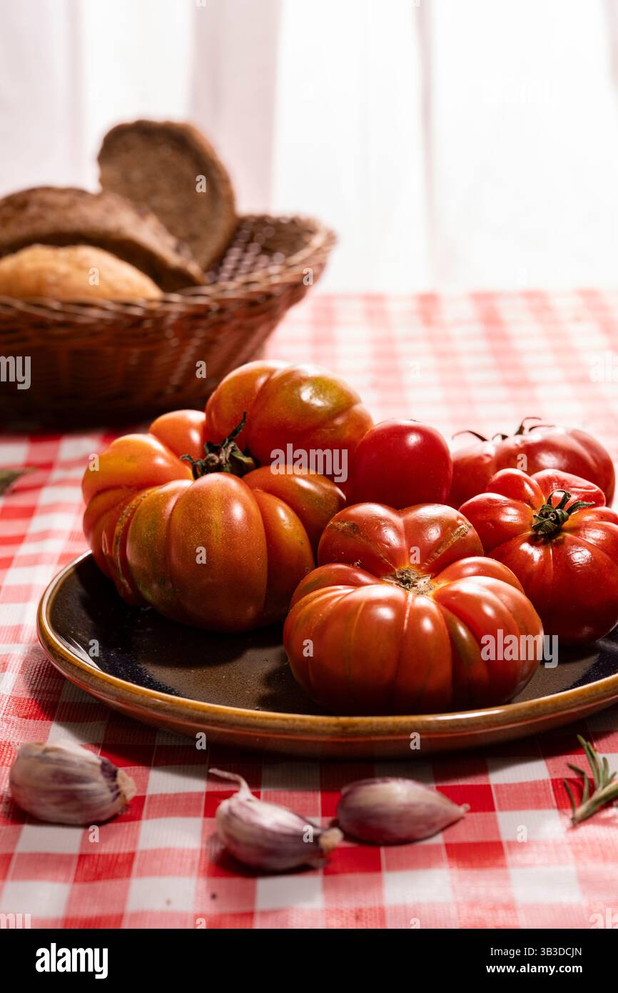 Frische Bio-Tomaten, Knoblauchzehen und rustikale Brotzutaten für die traditionelle mediterrane Bruschetta-Zubereitung. Stockfoto