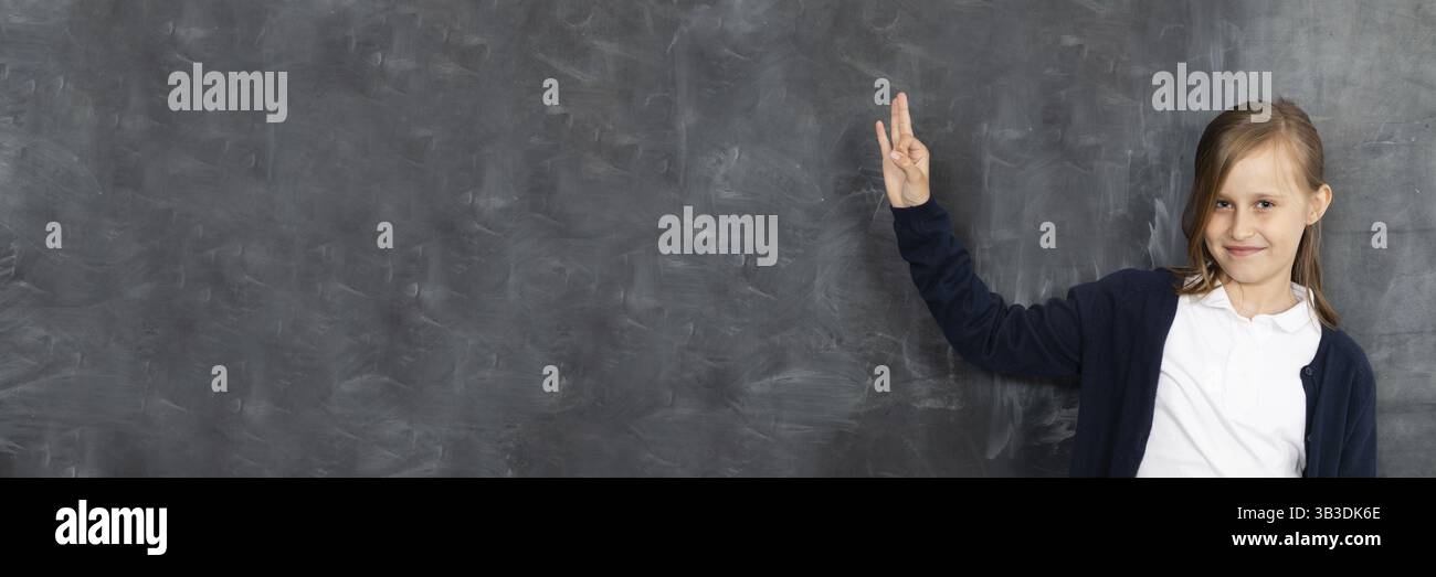 Das Schulmädchen erscheint auf einem leeren Schulausschuss. Er steht im Klassenzimmer an der Tafel. Jüngeres Mädchen. Panoramabild Stockfoto