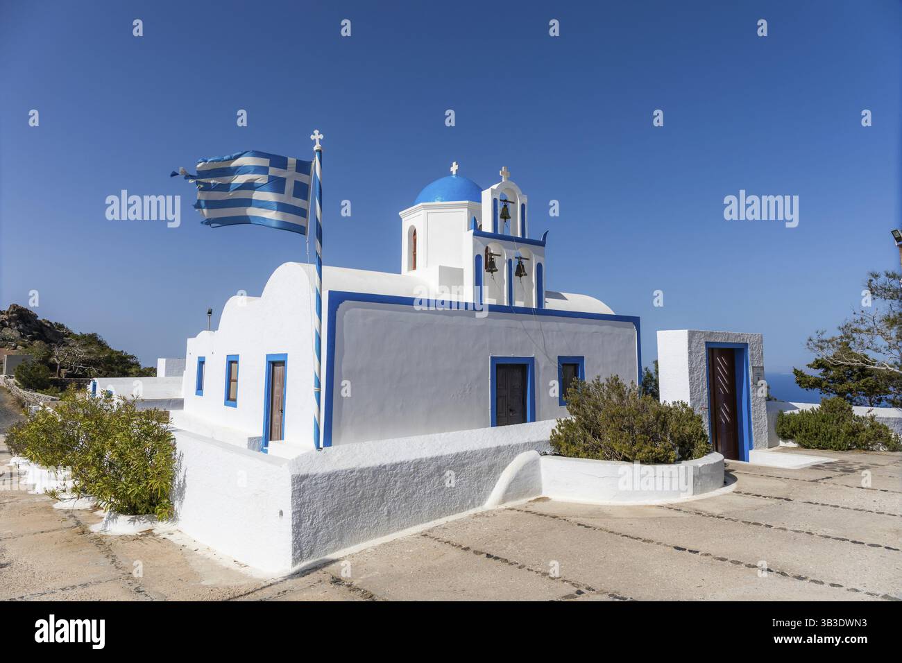 Griechische Flagge winkt im Wind, weiße Kirche, blaue Kirchenkuppel, Glockenturm, Insel Santorin, Griechenland, Europa Stockfoto
