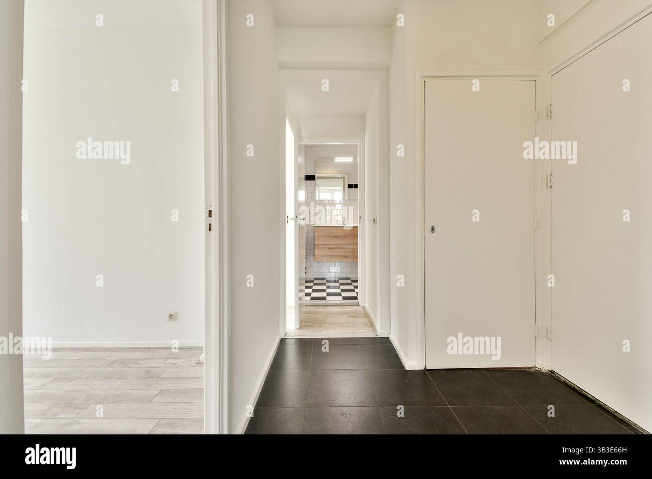 Ein eleganter und moderner Flur mit minimalistischen Designelementen. Der Raum bietet einen klaren Blick auf ein stilvolles Badezimmer mit klaren Linien und neutralen Farben. Stockfoto