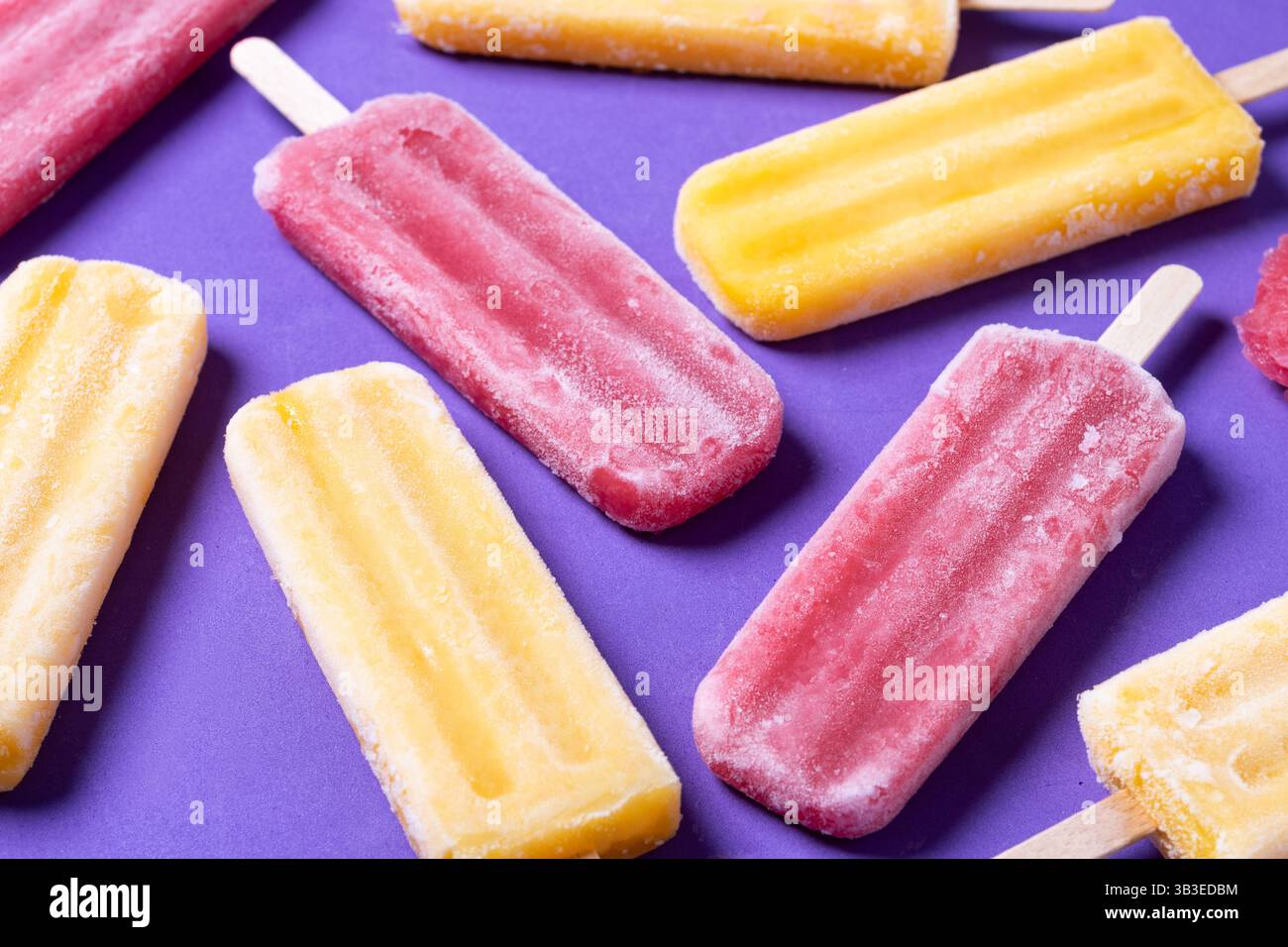 Rote Erdbeere und gelbe Stiele auf violettem Hintergrund Stockfoto