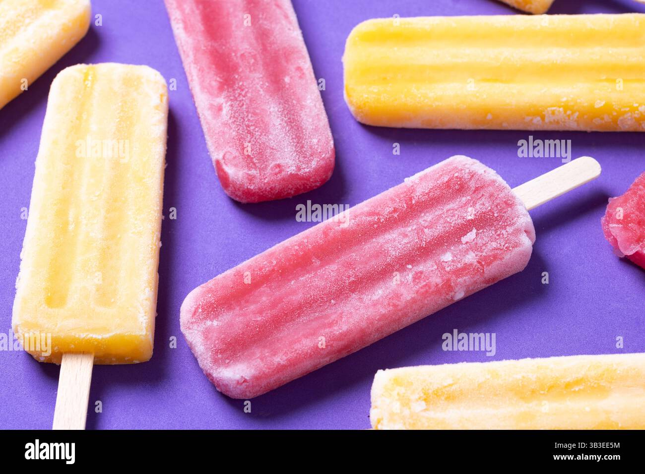 Rote Erdbeere und gelbe Stiele auf violettem Hintergrund Stockfoto