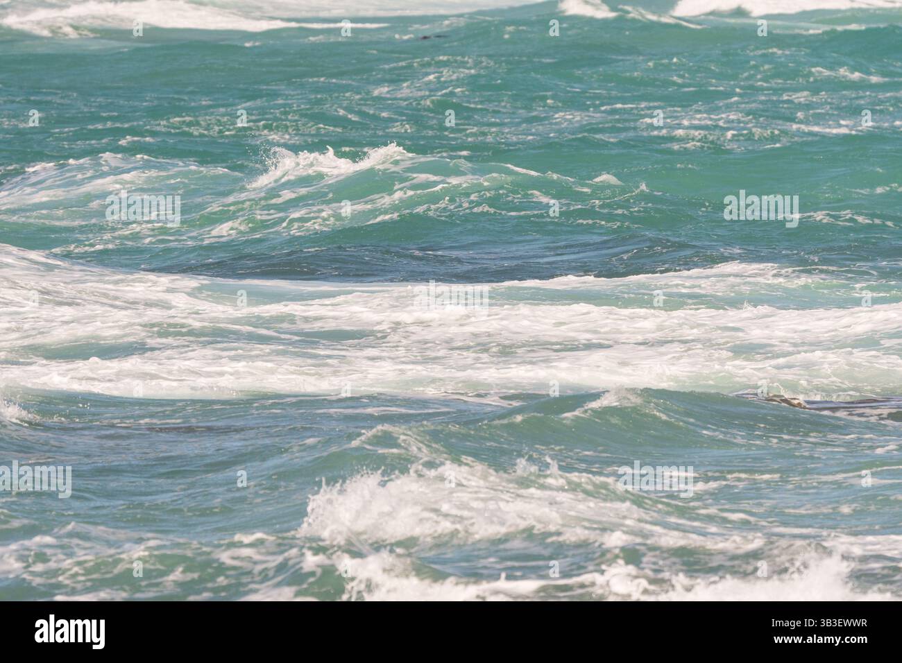 Blaues grünes Meerwasser, kleine Ozeanwellen, die von weißem Schaum gekrönt werden, zeigen Turbulenzen oder Bewegungskonzept abstrakten Naturhintergrund, Hintergrund Stockfoto