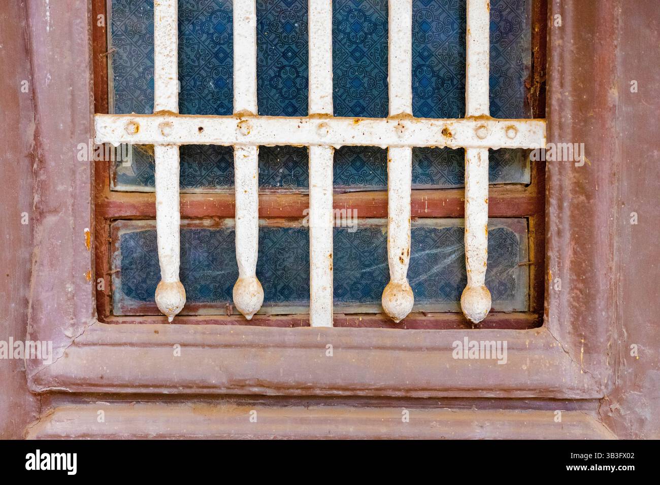 Nahaufnahme von Rosty Iron Bars auf Vintage-Fenster mit blauem gemustertem Glas in Ägypten Stockfoto