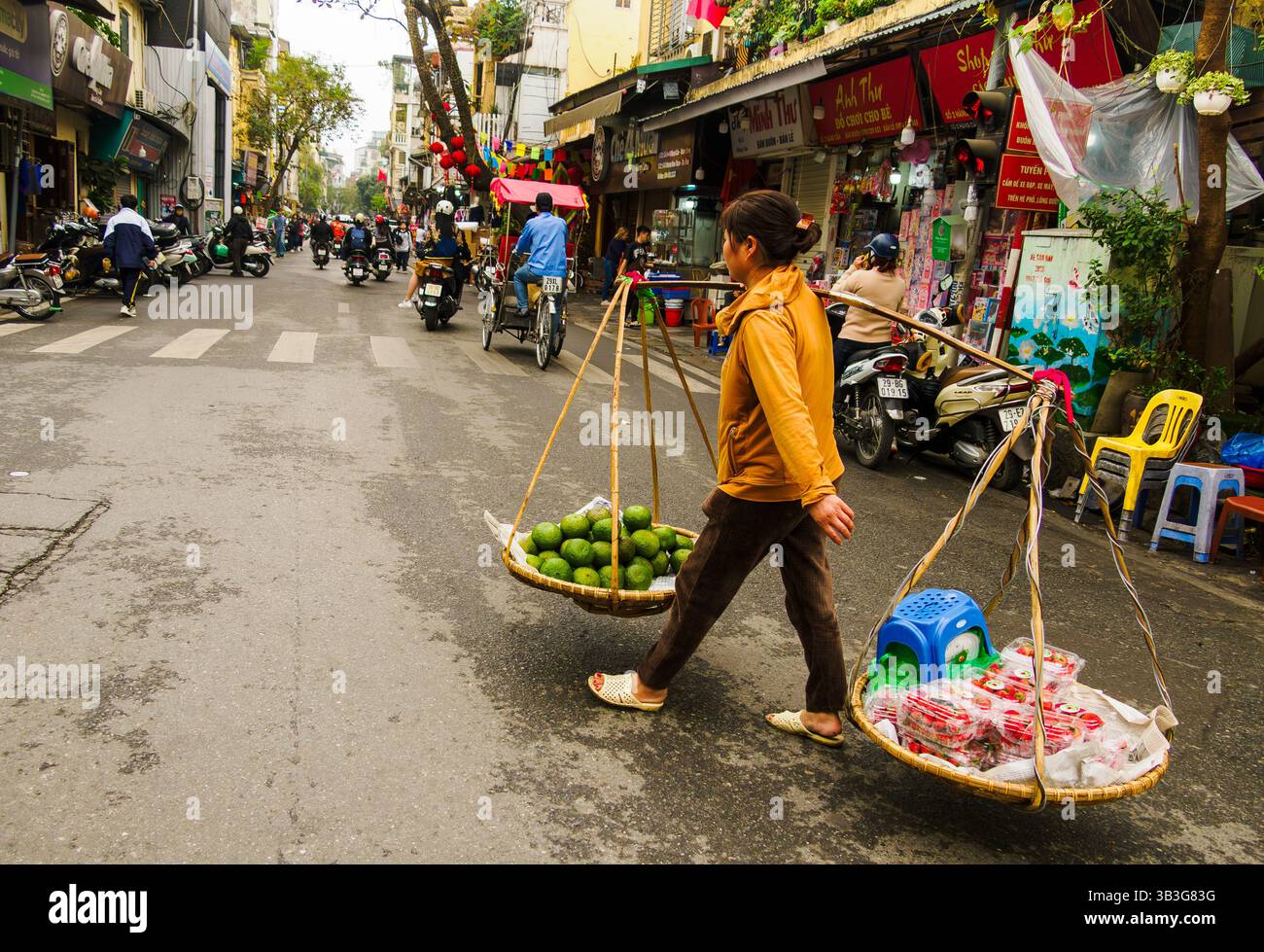 Eine Frau trägt Früchte zum Verkauf in Hanoi, Vietnam Stockfoto