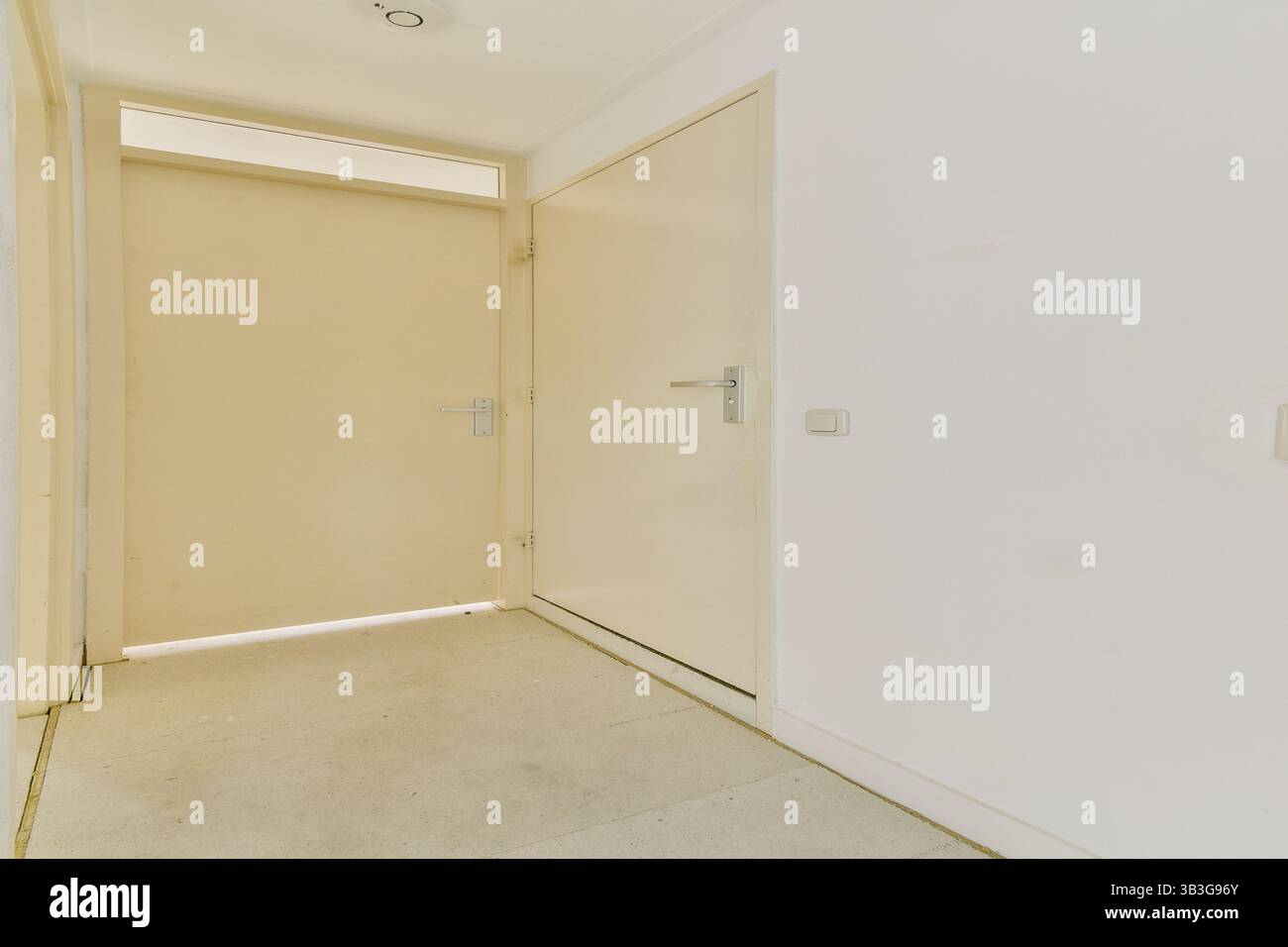 Ein klares und einfaches Design präsentiert einen modernen Inneneingang, der minimalistischen Stil mit neutralen Farben und sanfter Beleuchtung in diesem geräumigen Flur betont. Stockfoto
