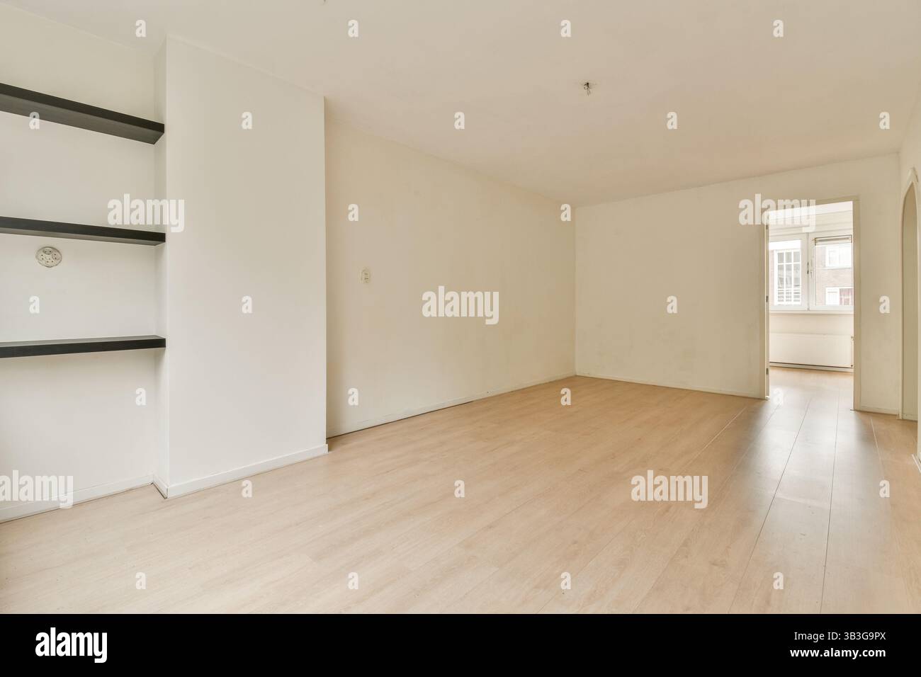 Ein geräumiger, leerer Raum mit hellem Holzfußboden und weißen Wänden, der eine saubere und minimalistische Ästhetik schafft. Ideal für die Inspiration des Innendesigns. Stockfoto