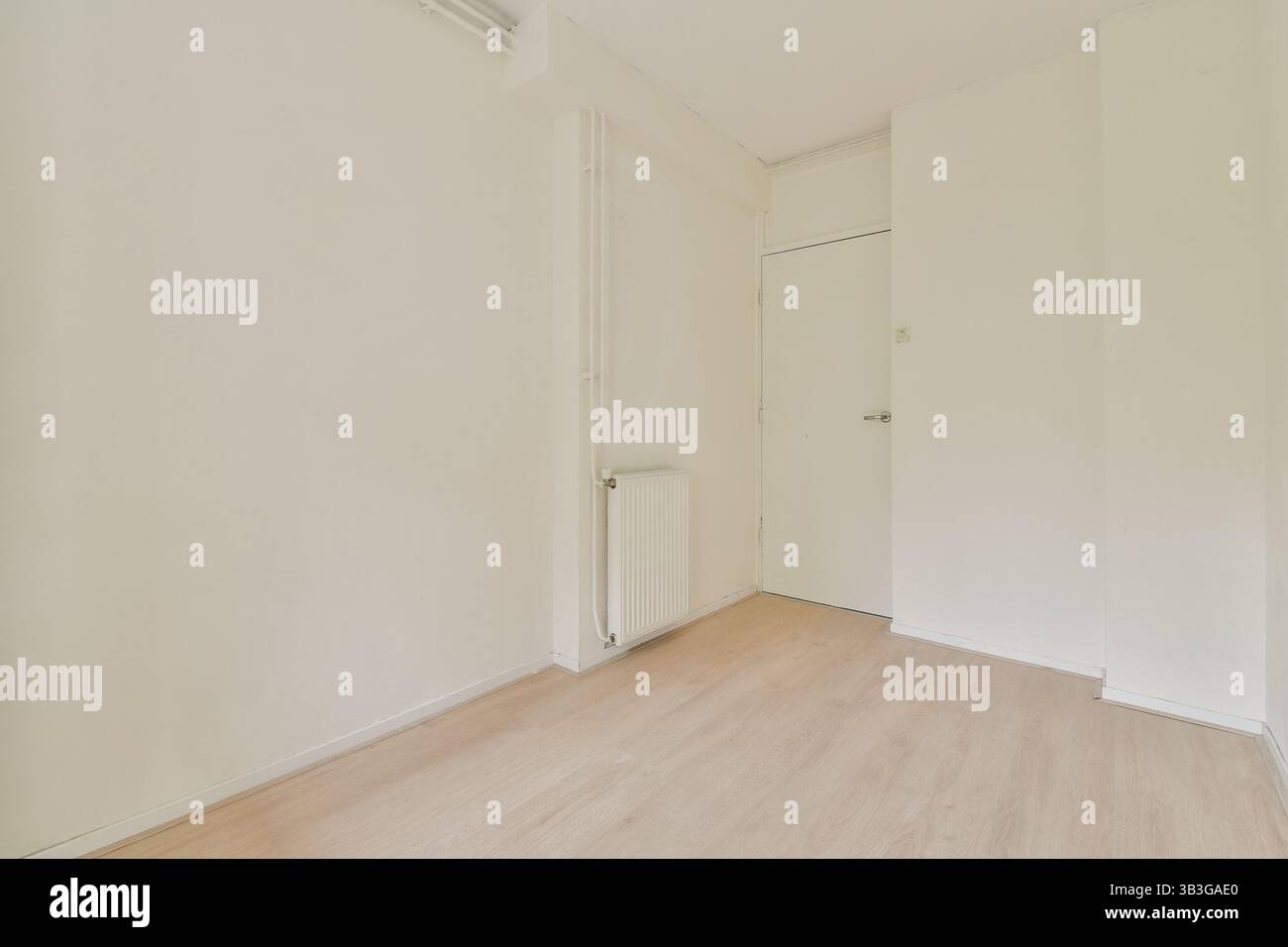 Ein geräumiges, minimalistisches Zimmer mit weißen Wänden und Holzfußboden, das Einfachheit und Ruhe ausstrahlt. Ideal für moderne Wohnkonzepte. Stockfoto