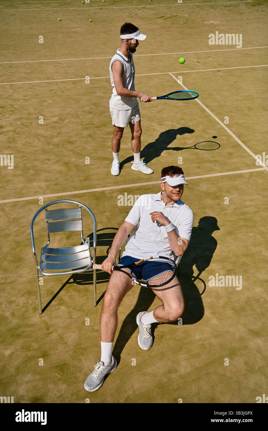 Zwei gutaussehende Männer üben ihre Tennisfähigkeiten an einem warmen Sommertag auf dem Platz aus. Stockfoto