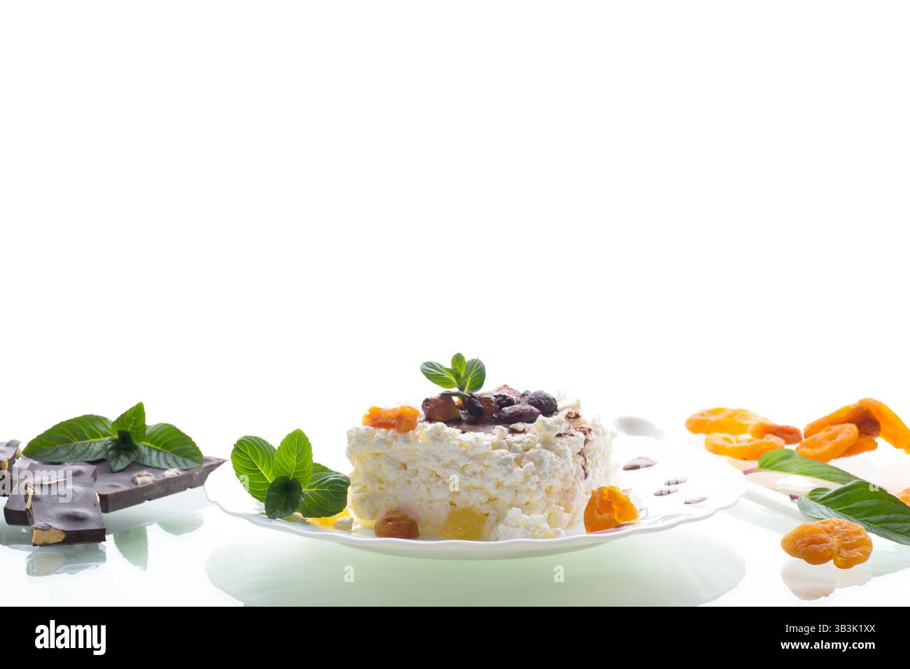 Hüttenkäse zum Frühstück auf einem Teller mit Schokoladensirup mit kandierten Früchten, isoliert auf weißem Hintergrund. Stockfoto
