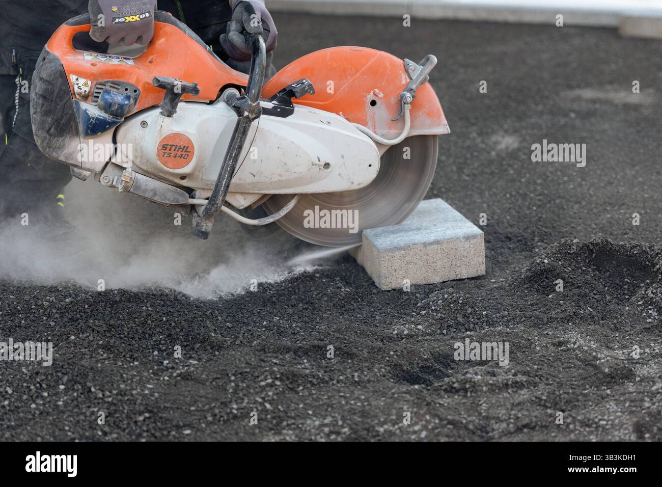 Fachkräftemangel im Baugewerbe harte Arbeit auf der Baustelle 29.04.25, Selters: Symbolfoto, Illustrationsbild, Symbolbild, Illustrationsfoto, Alltagsszene ein Bauarbeiter schneidet mit einer motorbetriebenen Trennscheibe Stihl TS 440 einen Betonstein zu symbolisch für die körperlich anspruchsvolle Arbeit im Baugewerbe. Die Szene steht exemplarisch für die Herausforderungen und den zunehmenden Fachkräftemangel in handwerklichen Berufen. Der Arbeitsplatz ist staubig, die Maschine schwer Arbeitsbedingungen, die immer weniger Menschen auf sich nehmen wollen. . Selters Hessen Deutschland *** Knappheit Stockfoto