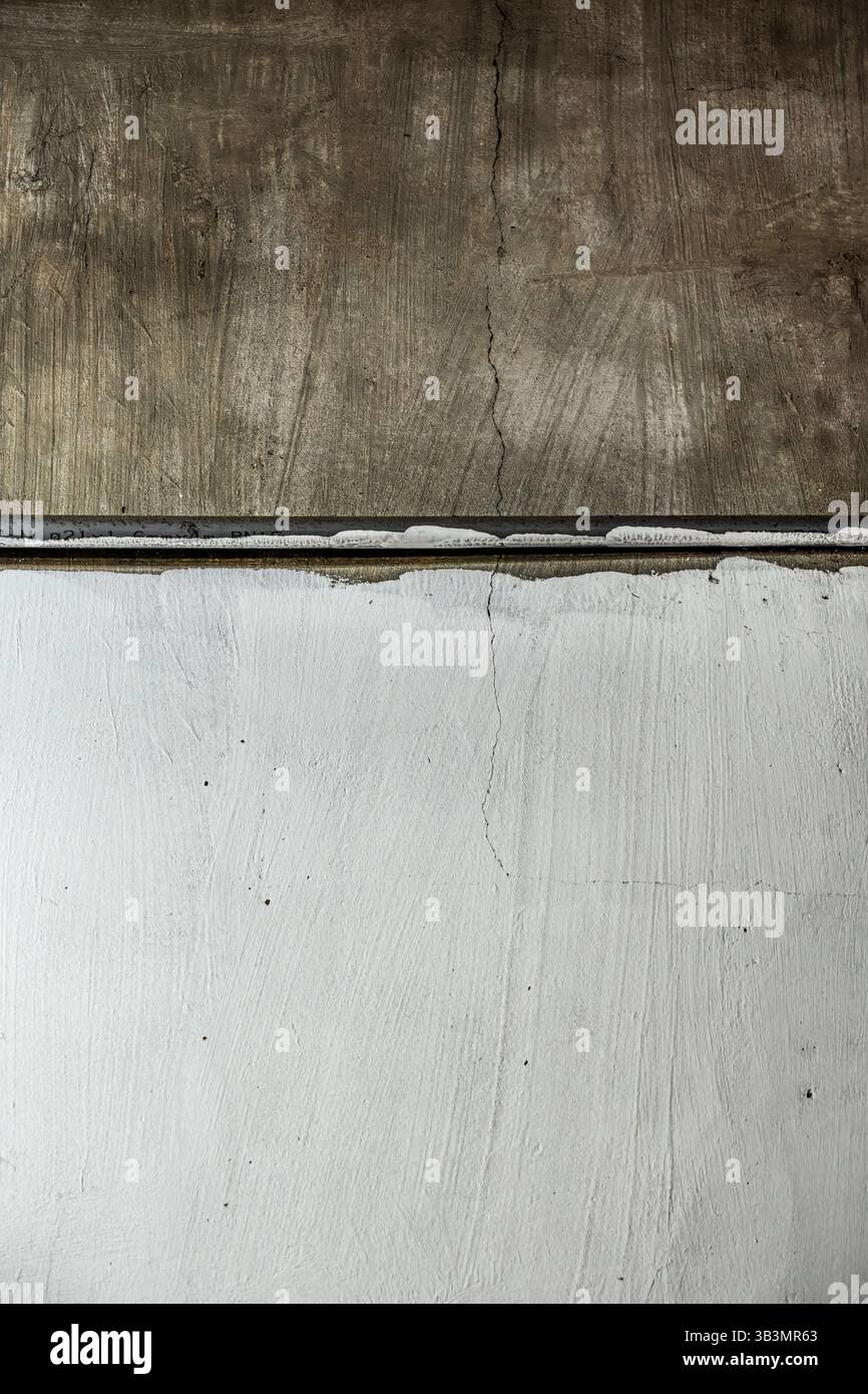 Strukturierte Betonwand mit sichtbaren Rissen und Lackschichten Stockfoto