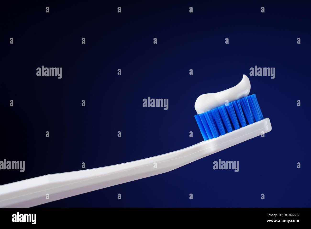 Das zahnärztliche Königskonzept. Hygiene. Professionelles Foto. Weiße Zahnbürste mit Zahnpasta auf dunkelblauem Hintergrund. Stockfoto