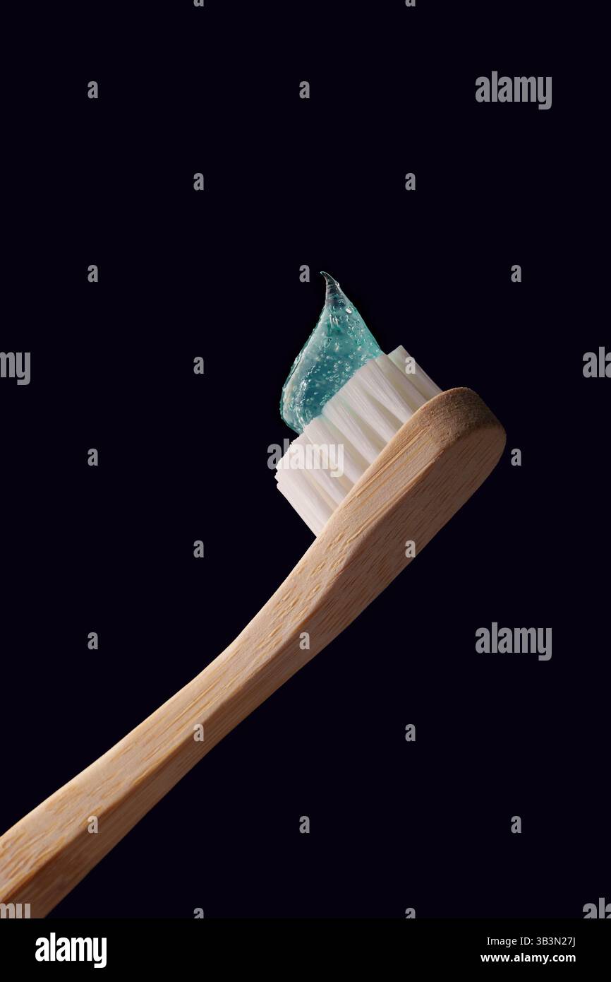 Bambuszahnbürste mit durchsichtiger blauer Zahnpasta auf dunkelblauem Hintergrund. Mundgesundheit. Stockfoto