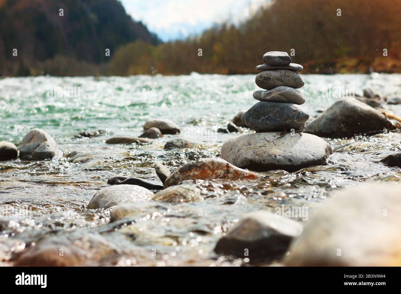 Ein brodelnder Gebirgsfluss mit großen Steinen, die Steine sind in einer Pyramide in der Mitte des Baches gestapelt, Konzept der Balance und Harmonie Stockfoto