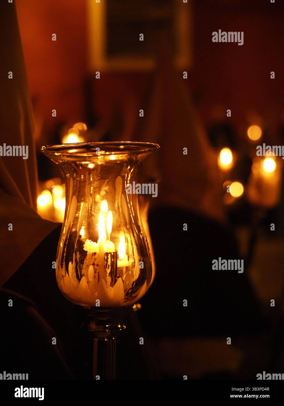 Eine Glühkerze brennt in einem Glashalter und strahlt ein warmes und heiteres Licht aus. Im unscharfen Hintergrund. Stockfoto