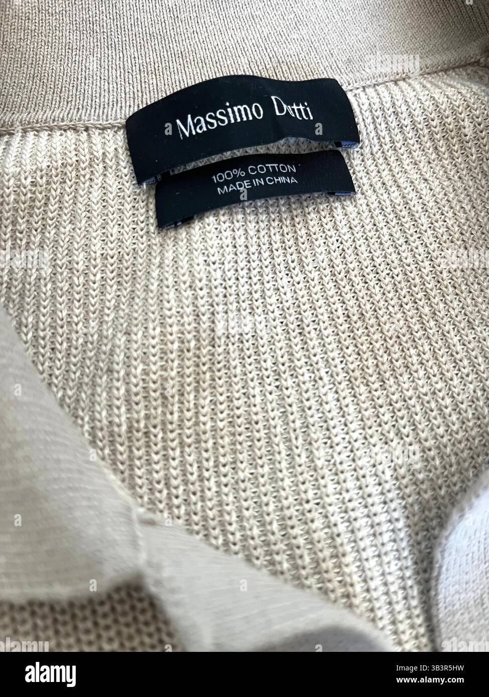 Nahaufnahme des Massimo Dutti Herrenbekleidung-Etiketts mit Made in China-Etikett, das den Herstellungsort des Kleidungsstücks angibt, 100 % Baumwolle hergestellt Stockfoto