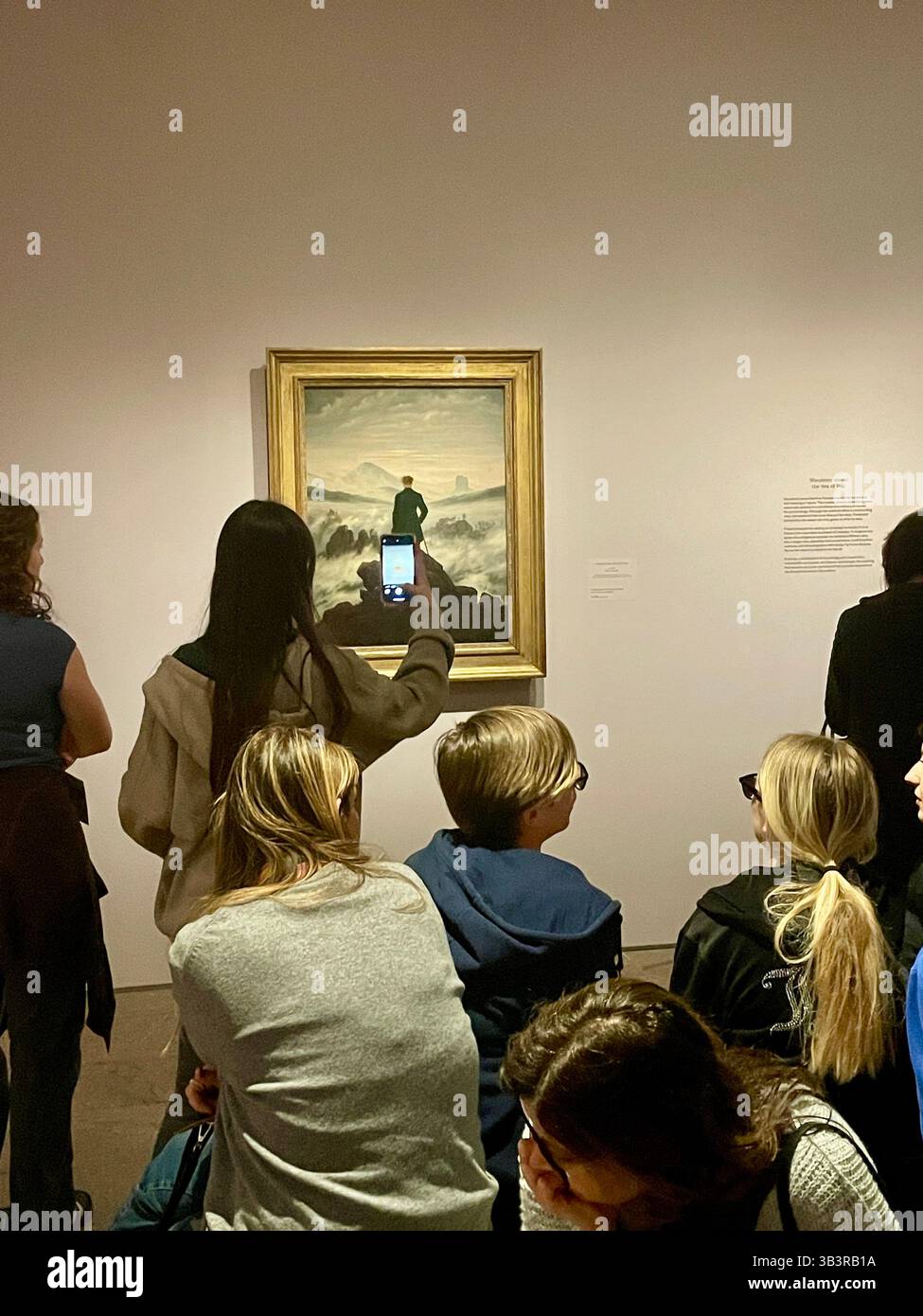 Besucher bewundern den Wanderer über dem Nebelmeer, 1818 in der Sonderausstellung The Soul of Nature, TRAF Caspar David Friedrich, 2025, NYC. USA - Smartphone-aufgenommenes Stockfoto