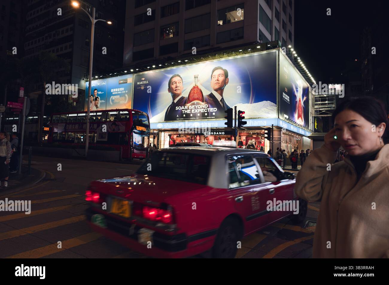 Rotes Taxi verschwimmt an hellen Reklametafeln in der nächtlichen Innenstadt vorbei Stockfoto
