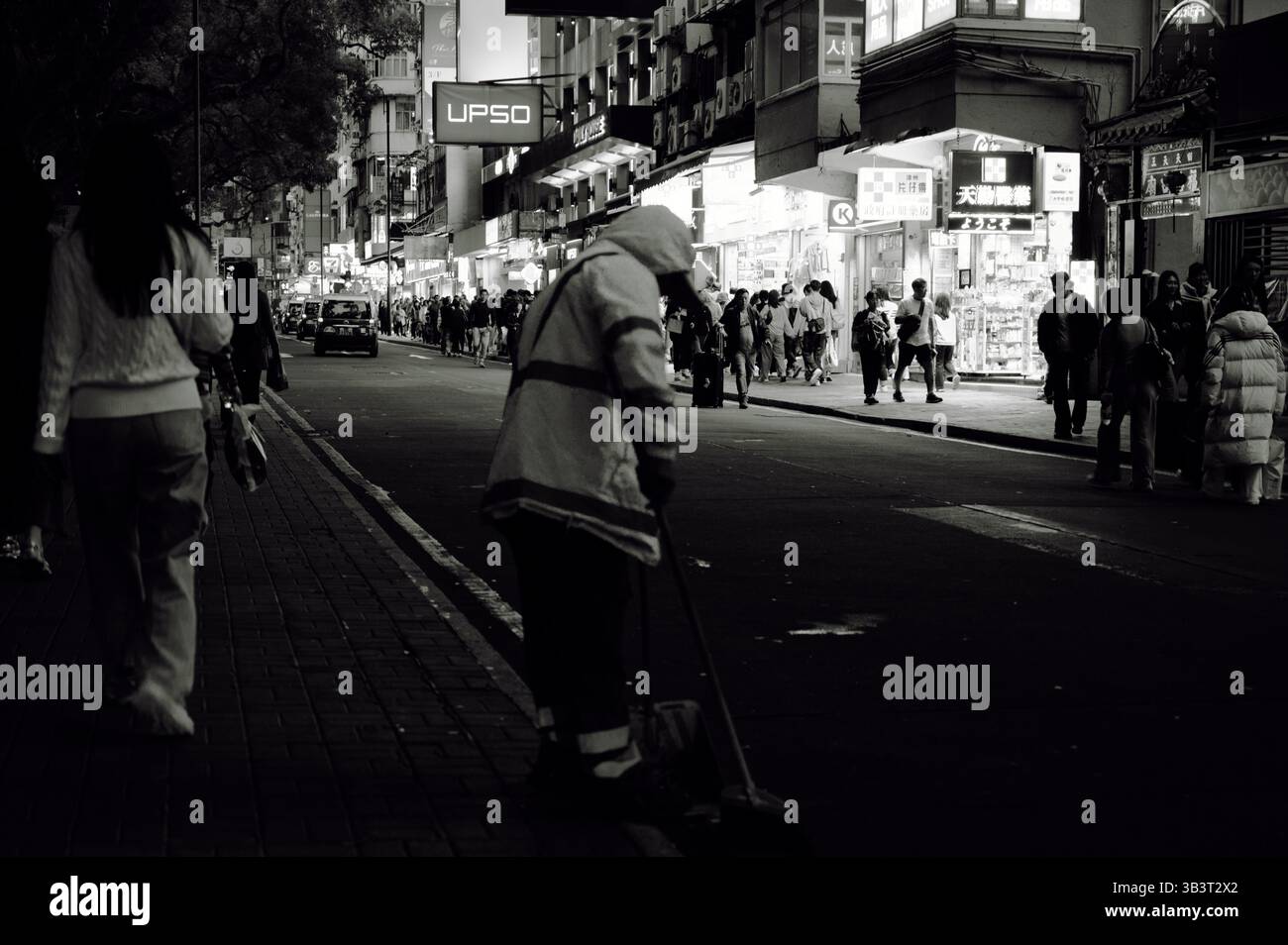 Einsamer Straßenreiniger durchstreift das geschäftige Nachtleben in Hongkong Stockfoto