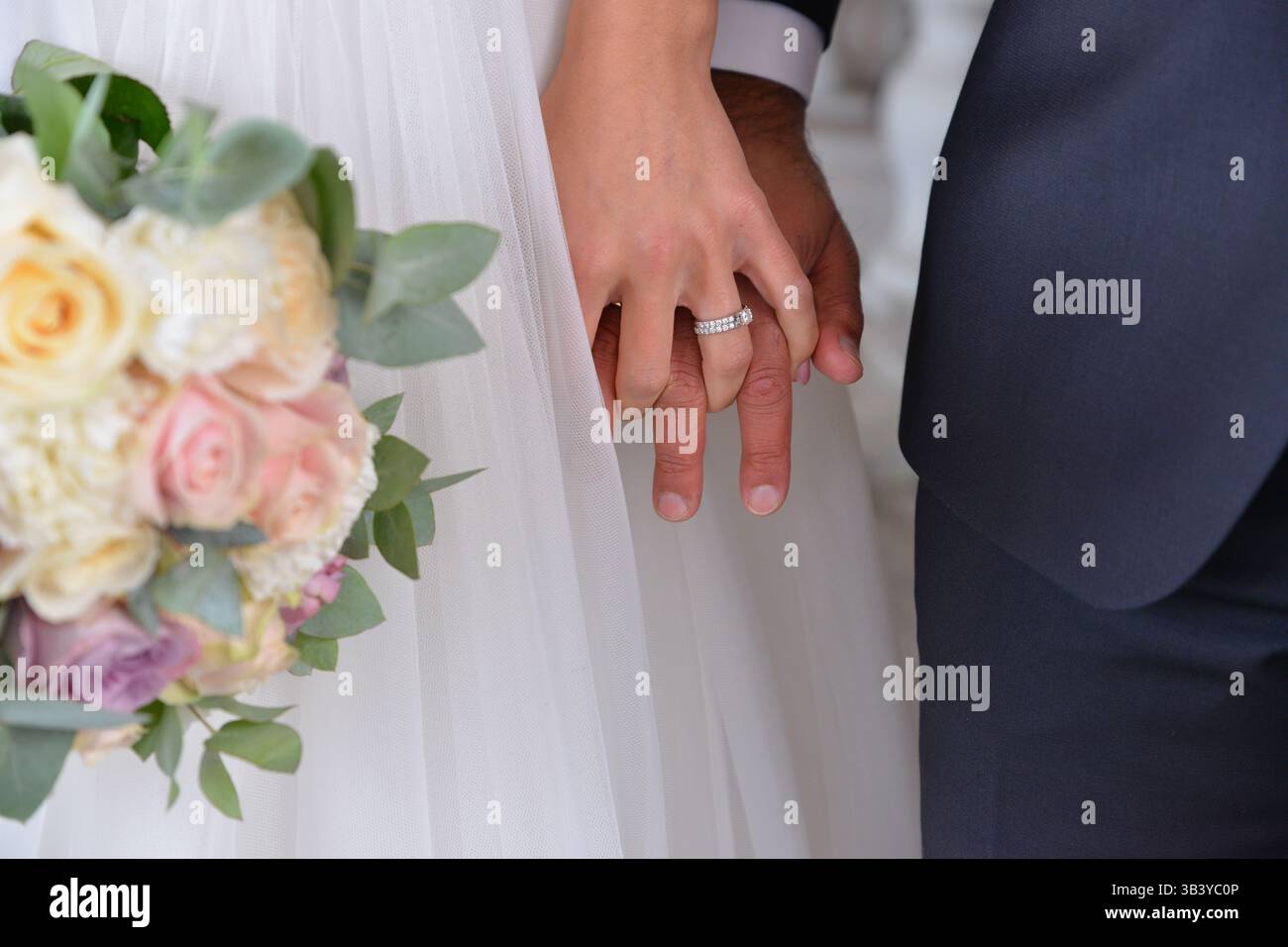 Hände der Braut und des Bräutigams mit Ringen an einem Hochzeitsstrauß in Schweden Stockfoto