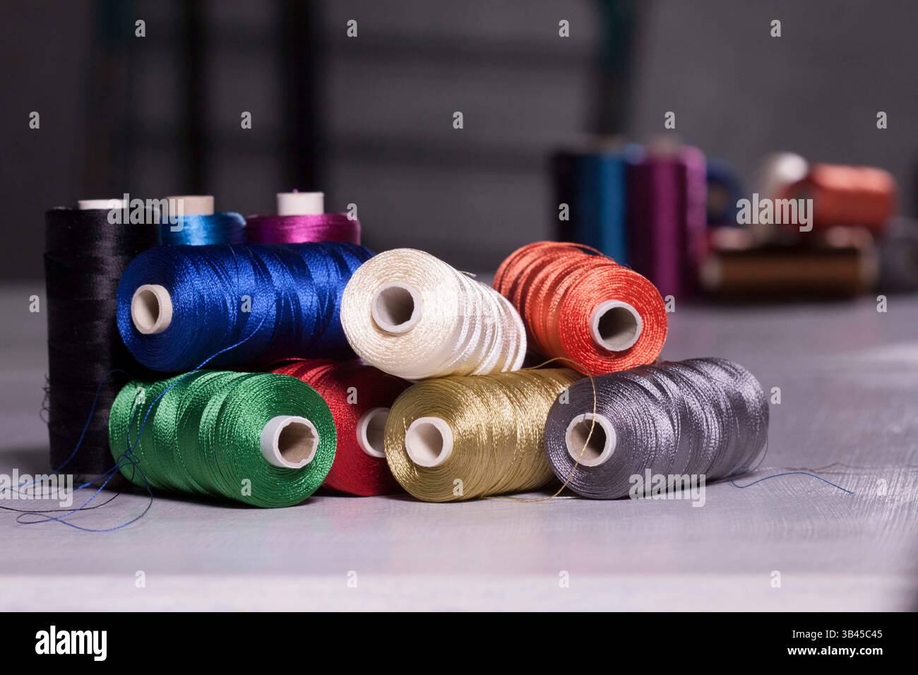 Gruppe von Metallspulen färbt auf dem Tisch liegende Gewinde. Nähwerkzeuge für den professionellen Kleidermacher oder für das Hobbynähen. Stockfoto