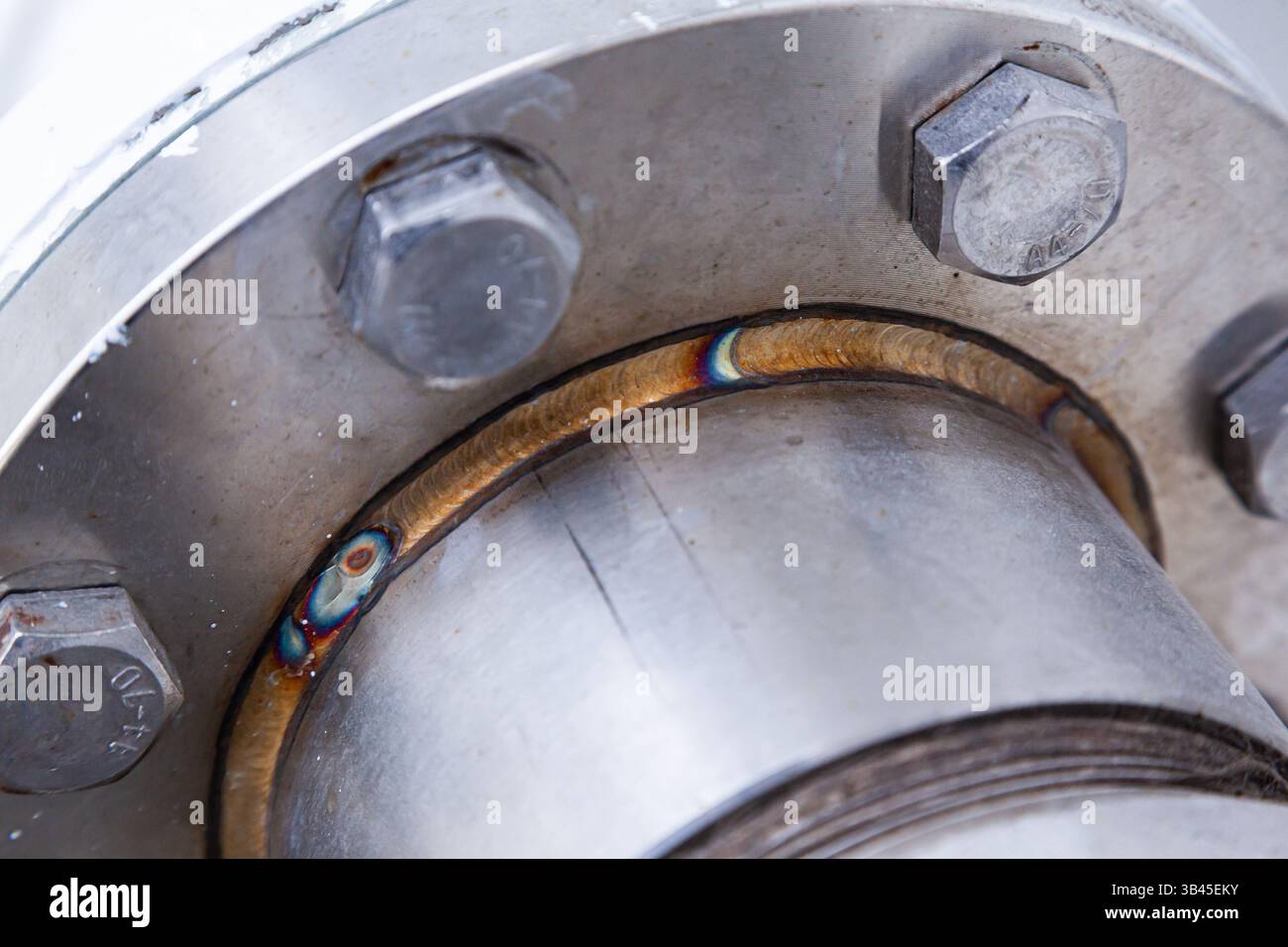 Ein Abschnitt eines geschweißten Rohrs mit einem Edelstahlflansch mit eingeschraubten Schrauben. Stockfoto