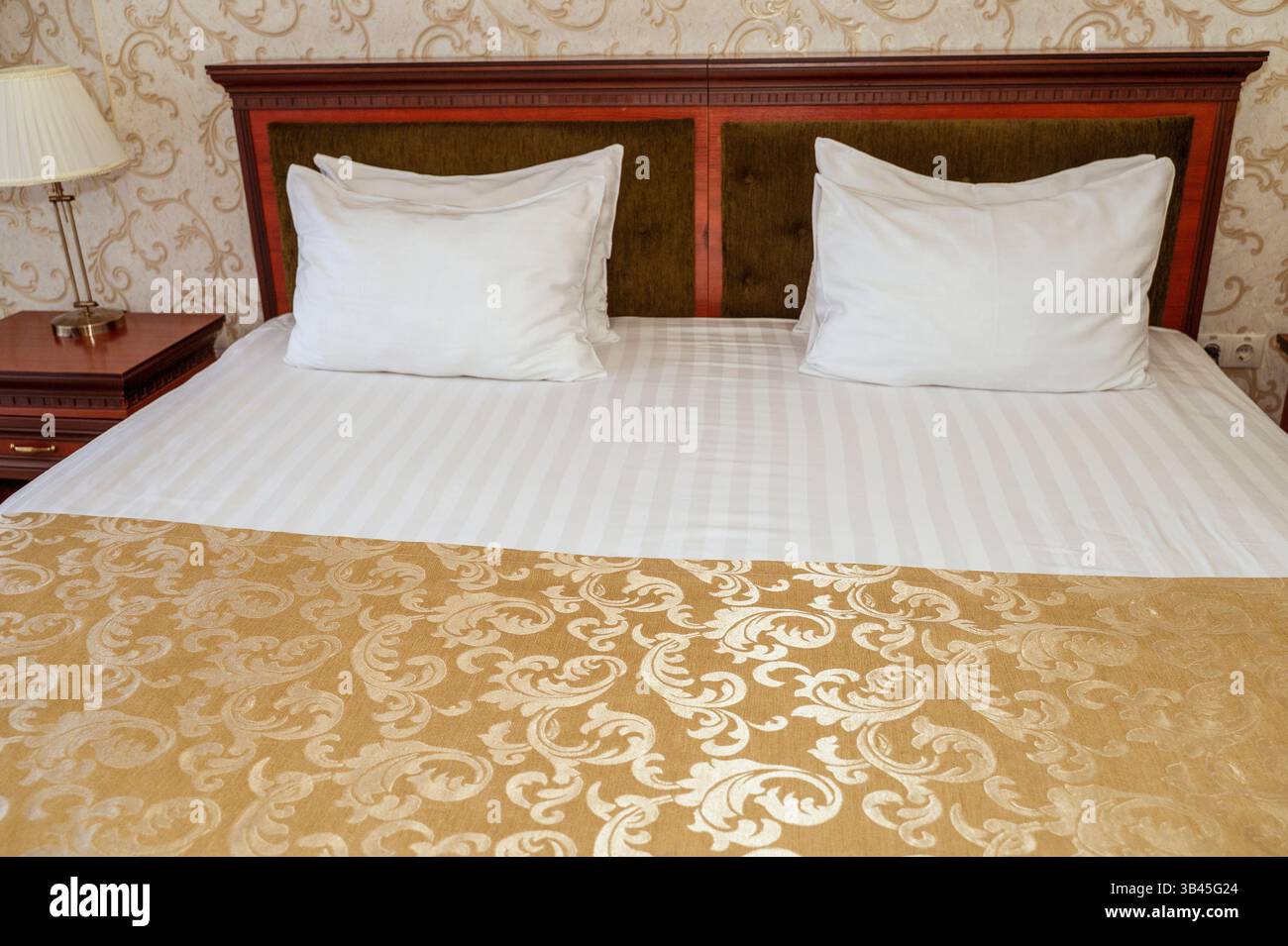 Doppelbett mit dunkelrotem Holz, Kopfteil, sauberer weißer Bettwäsche und Kissen Stockfoto