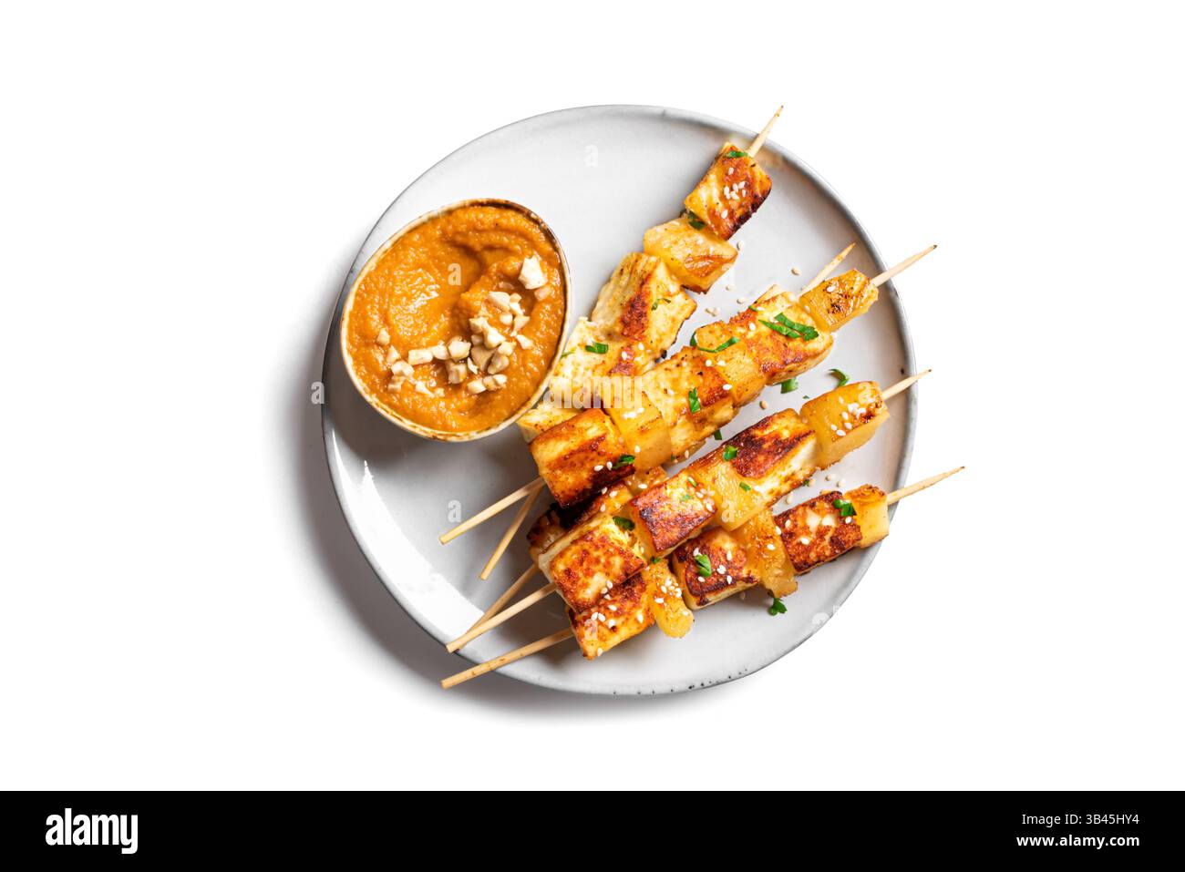 Gegrillter Tofu- und Ananassatay-Spieß mit würziger Erdnusssoße auf Teller isoliert auf weißem Backgound, Blick von oben. Gebratene halloumi-Käsekebabs. Vegan V Stockfoto