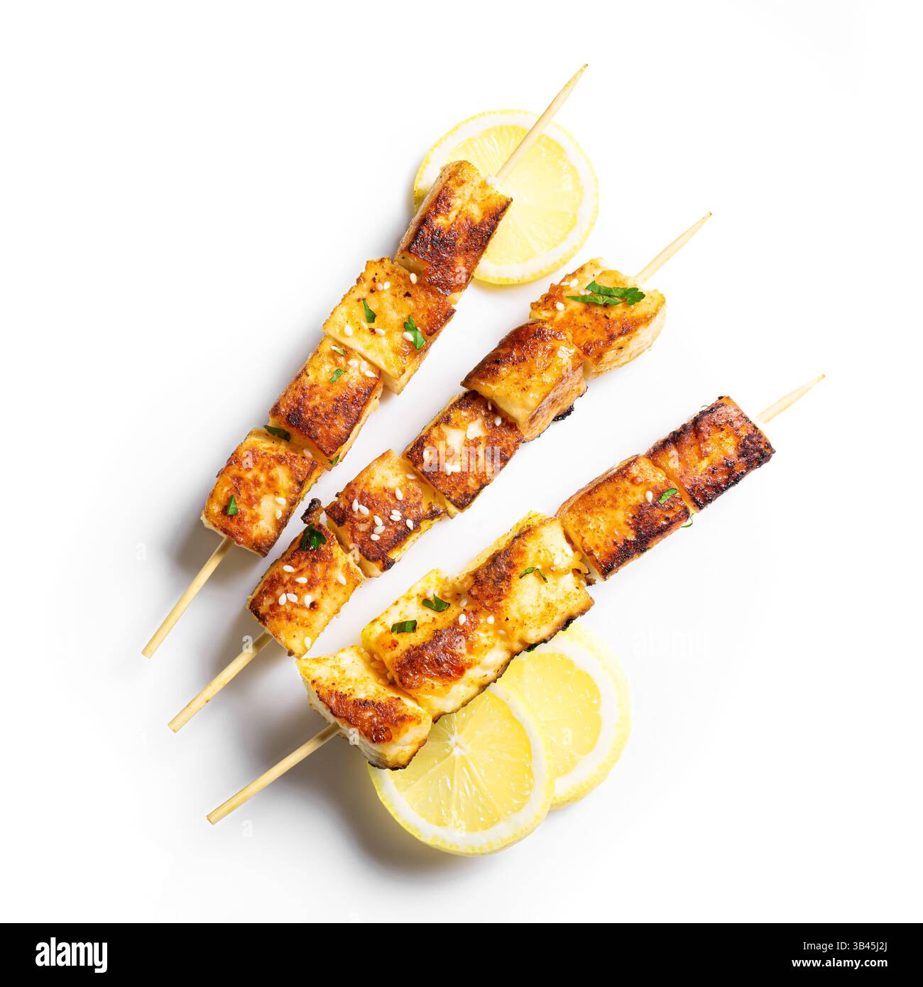 Gegrillter Tofu-Satay-Spieß mit Zitronenscheiben isoliert auf weißem Background, Blick von oben. Gebratene halloumi-Käsekebabs. Veganes vegetarisches Essen. Stockfoto