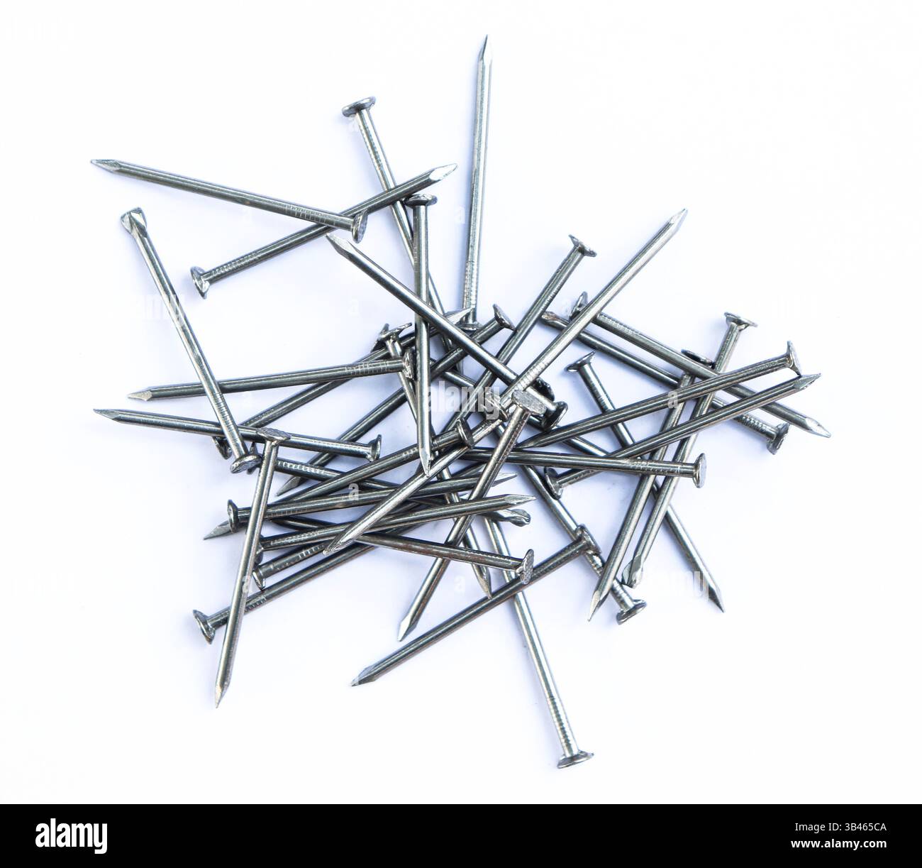 Bei der Nahaufnahme sind mehrere silberne Metallnägel verstreut. Sie haben scharfe Spitzen und flache Köpfe. In einem Haufen auf einer hellweißen Oberfläche angeordnet. Stockfoto