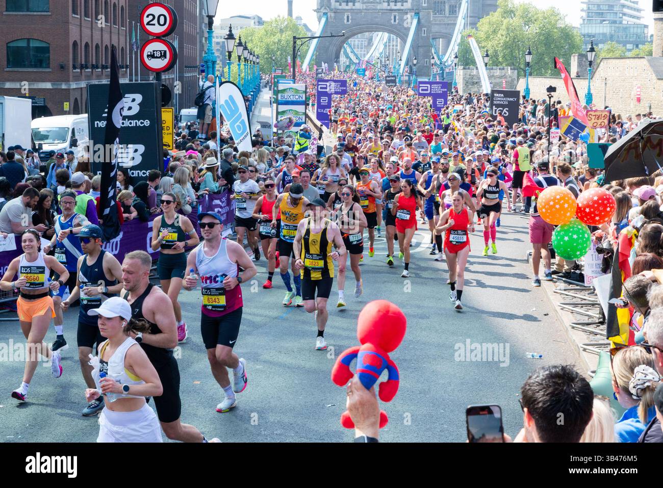 Lustige Läufer, die 2025 beim TCS London Marathon antreten, durchqueren Tower Hill, London, Großbritannien, nach Tower Bridge mit Unterstützern Stockfoto