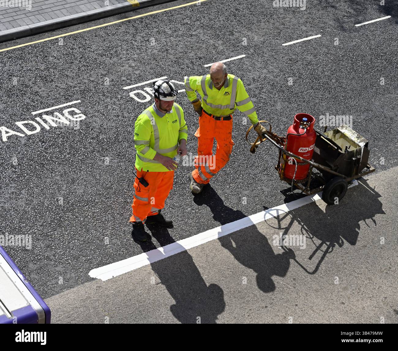 Zwei Handwerker in gut sichtbarer Kleidung mit Straßenstrich-Lackiermaschine Stockfoto