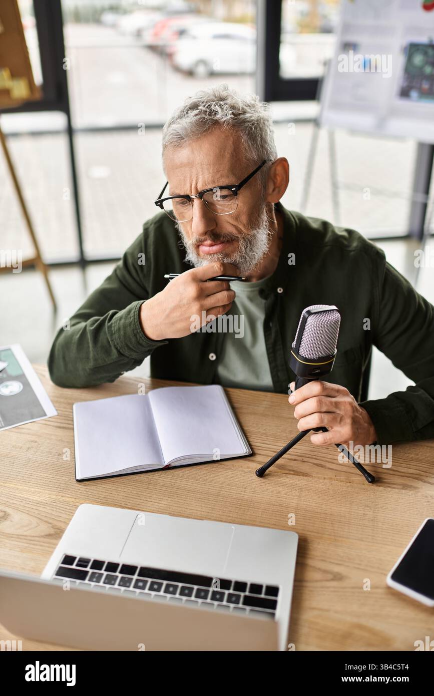 Ein Profi reflektiert während er Notizen für eine Podcast-Aufnahme in einem eleganten Arbeitsbereich vorbereitet. Stockfoto