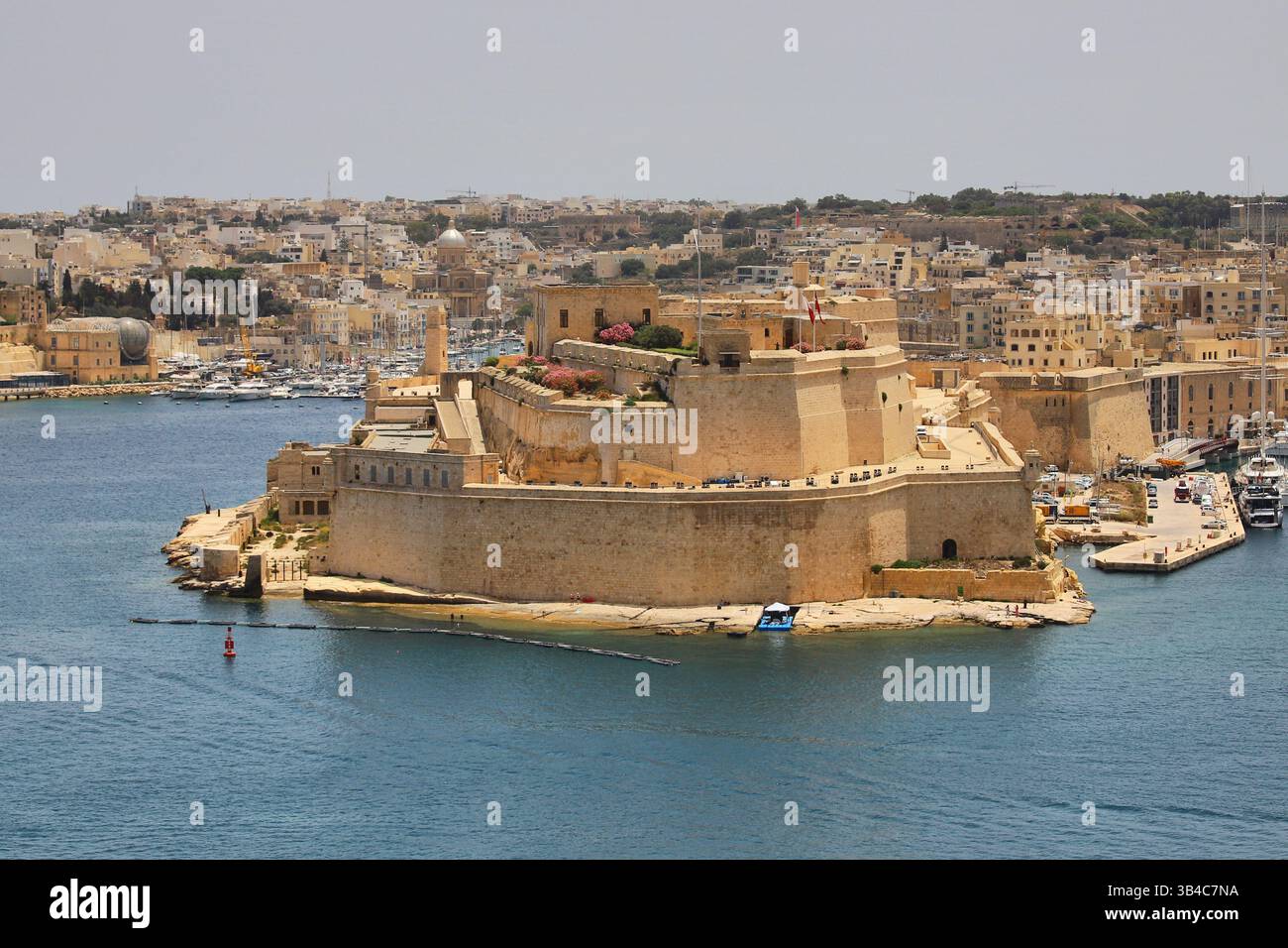 Historisches Fort St. Angelo in Birgu, Malta, umgeben von blauem Wasser und Yachten, mit Senglea und Cospicua im Hintergrund. Stockfoto