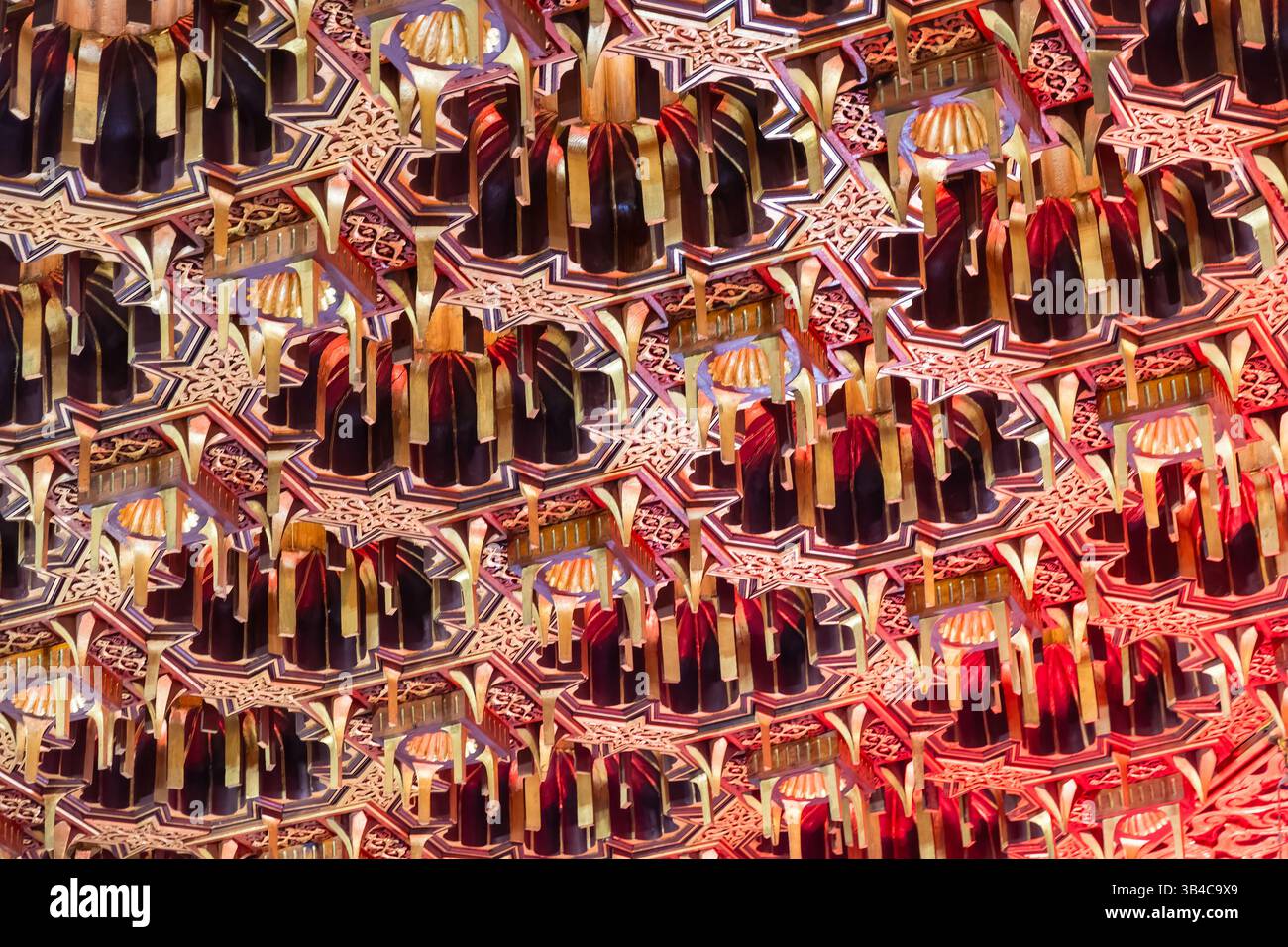 Detailreich verzierte Decke mit geometrischen und floralen Mustern in Gold- und Rottönen. Das Design zeigt traditionelle islamische Architekturelemente Stockfoto