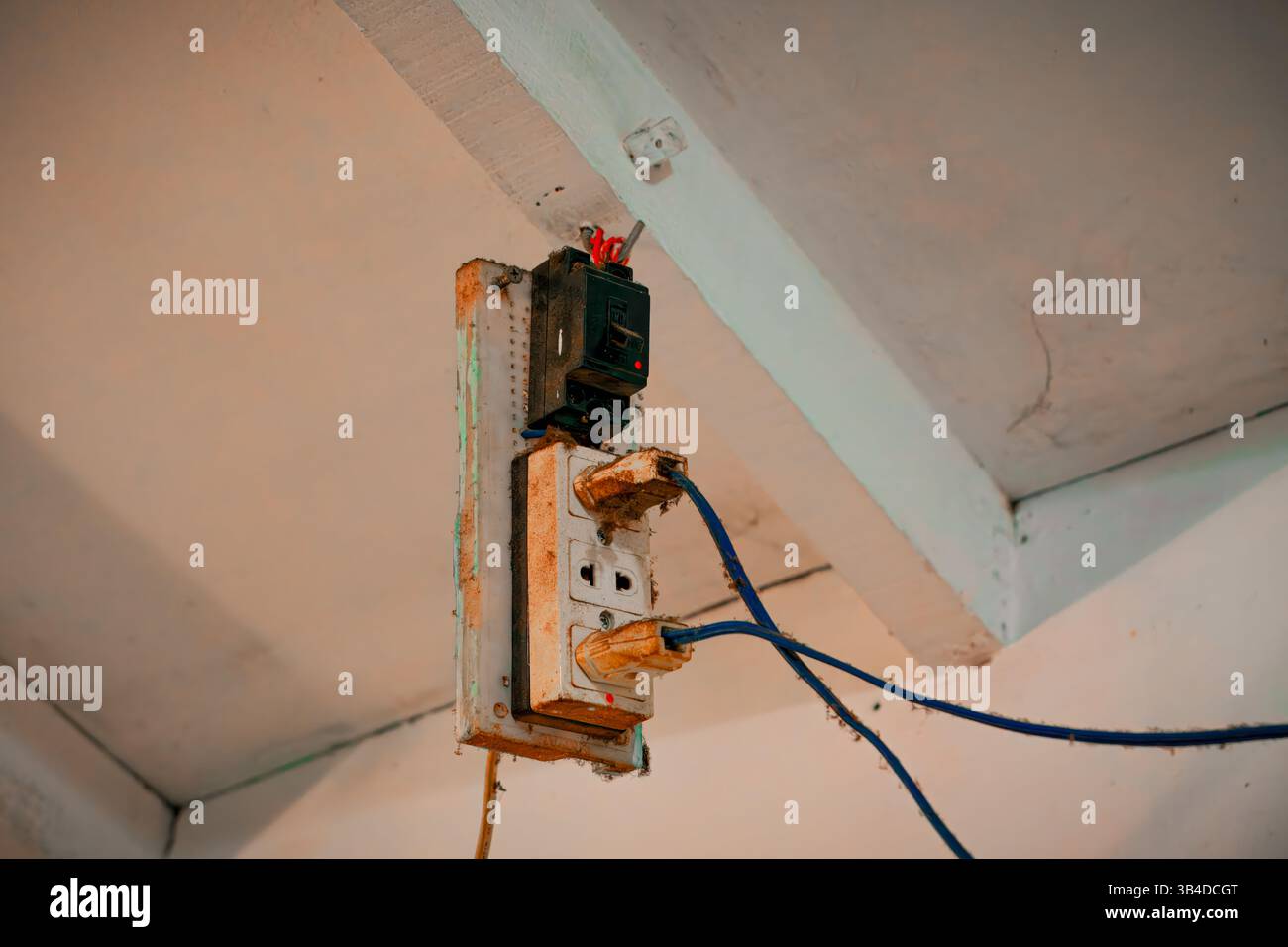 Rostige Steckdose mit freiliegenden Drähten an der Decke Stockfoto