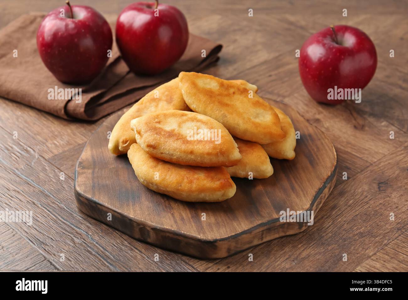 Köstliche gebratene Pyrizhky (gefüllte Kuchen) und Äpfel auf Holztisch, Nahaufnahme Stockfoto Köstliche gebratene Pyrizhky (gefüllte Kuchen) und Äpfel auf Holztisch, Nahaufnahme Stockfoto