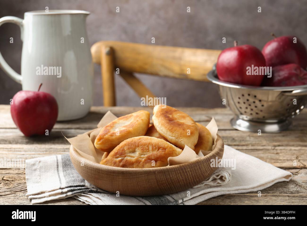 Köstliche gebratene Pyrizhky (gefüllte Kuchen) und Äpfel auf Holztisch, Nahaufnahme Stockfoto Köstliche gebratene Pyrizhky (gefüllte Kuchen) und Äpfel auf Holztisch, Nahaufnahme Stockfoto