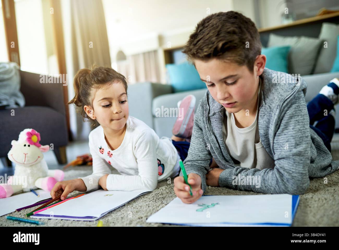 Kinder, Geschwister und Malaufgaben zu Hause, Bücher und künstlerische Aktivitäten für kreative Bildung. Kinder, die zusammenziehen und sich auf dem Boden kleben Stockfoto